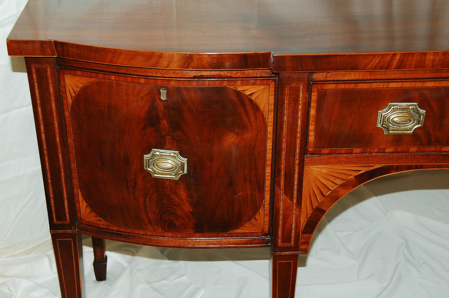 English Hepplewhite breakfront bowfront mahogany inlaid sideboard with inlaid tapered legs ending in Marlborough feet. This 70 inch long sideboard has wonderful timber and classic inlay. The fan inlay made of shaded boxwood frames the arch under the