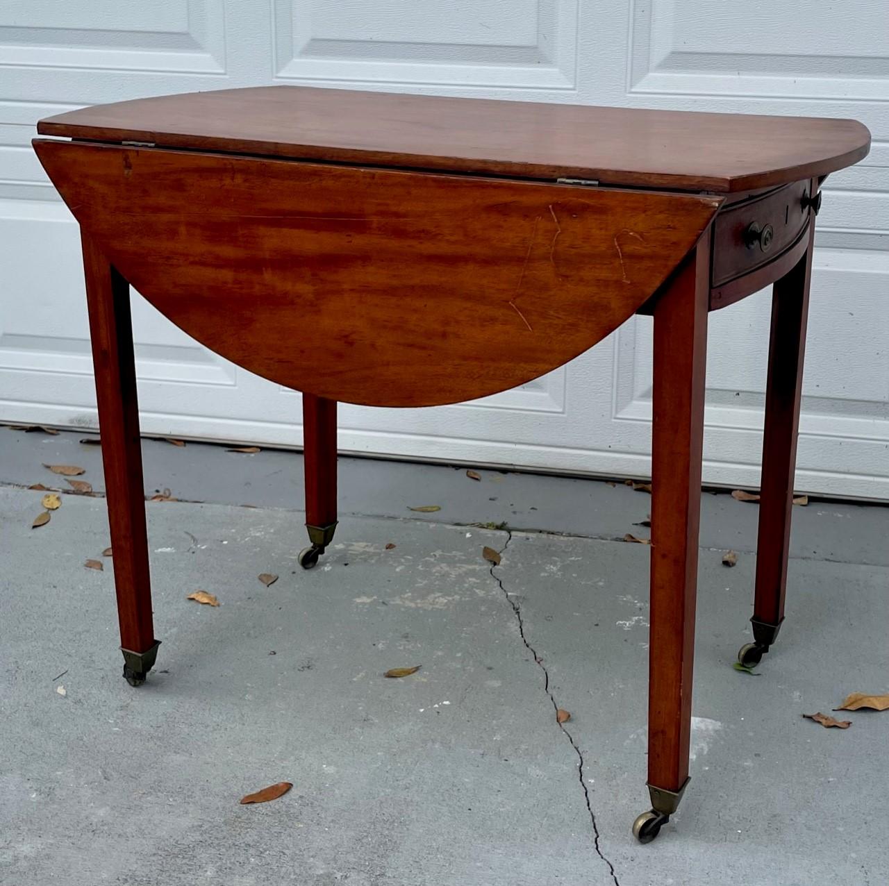 English Early 19th Century Mahogany Pembroke Table.

Early 19th century Mahogany oval occasional Pembroke table. It has two drop leaves, supported by hinged brackets over one single drawer with brass pulls. It sits above four tapering legs with