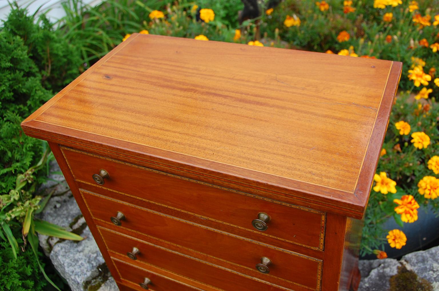 English early 19th century mahogany and satinwood child's chest of drawers. This small chest has a satinwood top, banded with mahogany and strung with boxwood; the rest of the carcass is in mahogany. Each of the four drawers has intricate narrow