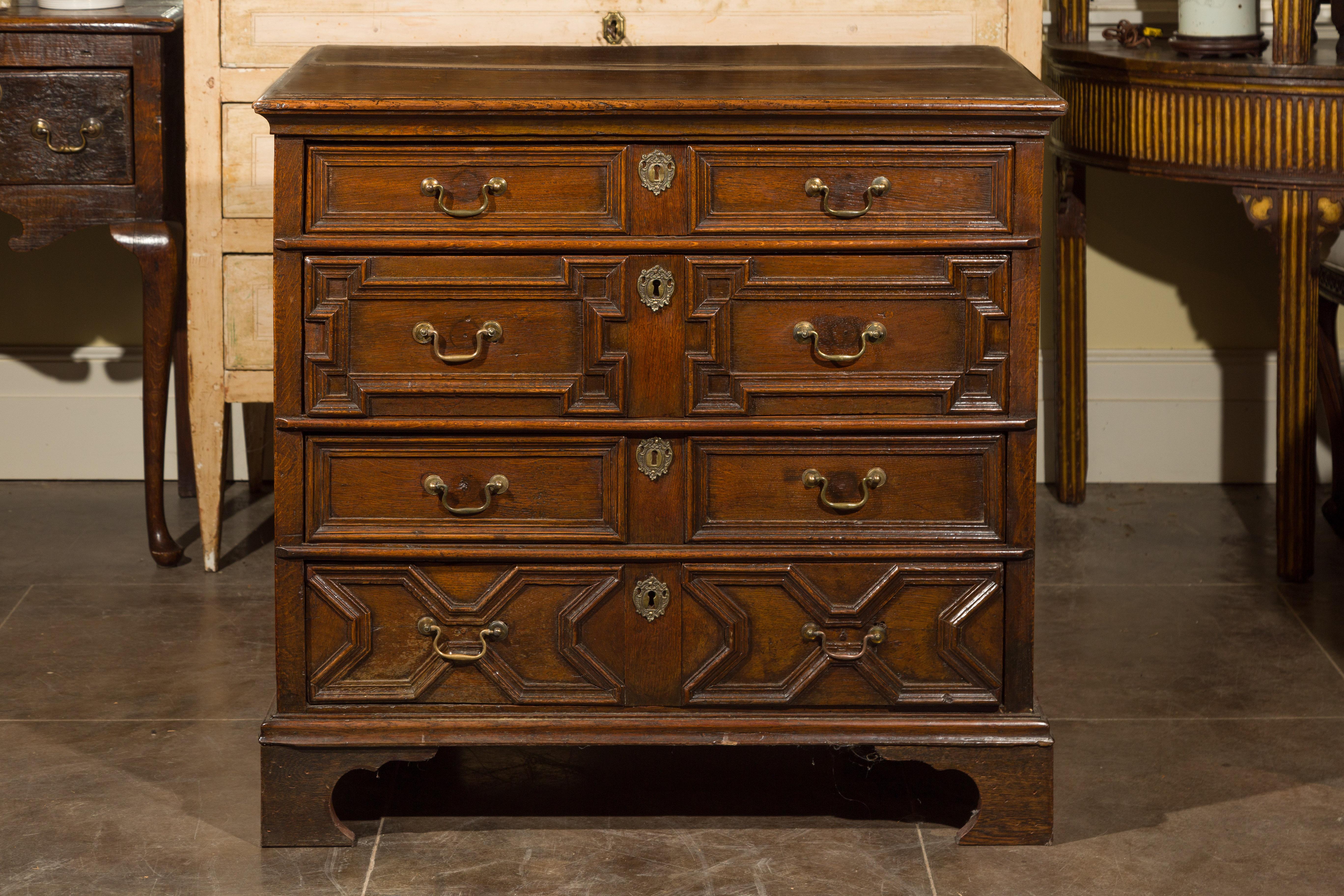 This English Georgian period early 19th century geometric front oak chest features a rectangular top with rounded edges over four dovetailed drawers, grooved on the side for the runner. The geometric drawers discreetly alternate to provide a nice