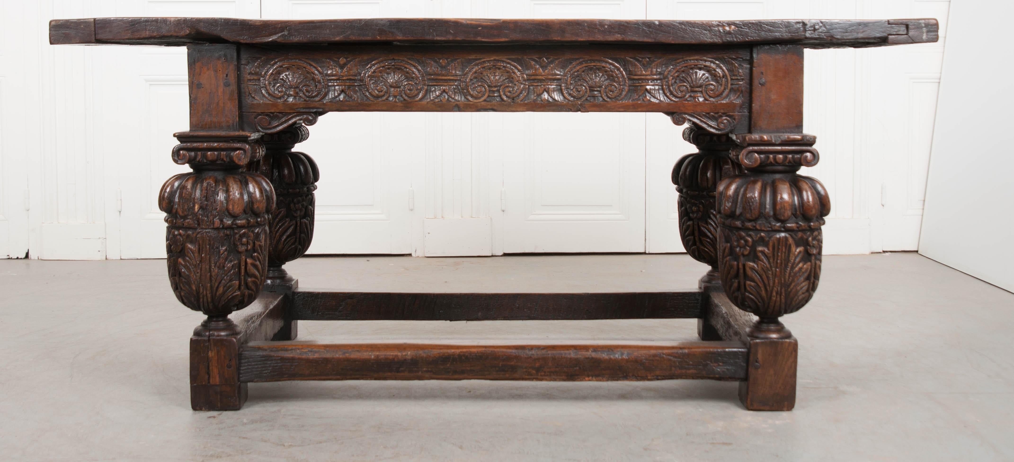 This exuberantly-carved Spanish oak refectory table, circa 1800, will add a rich and bold statement to any room it’s placed. The cleated plank top, above a scroll-carved frieze, is raised on bulbous gadroon-and-foliage carved cup and supports.