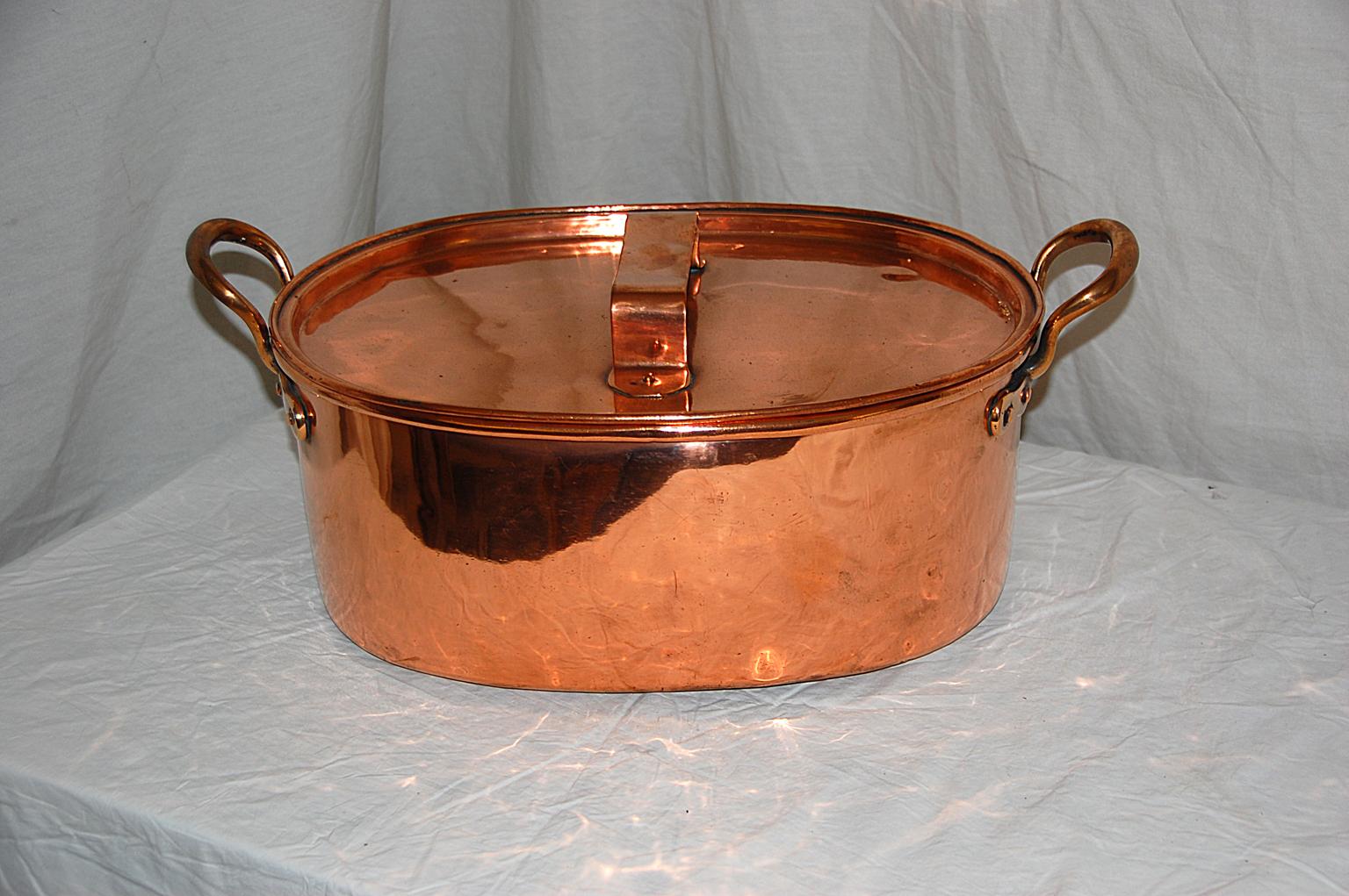 English early 19th century oval copper roasting pan or cauldron with lid. This heavy gauge copper pan is of dovetailed construction, with rolled edge, cast handles, and lift off lid with loop handle. This pan was used to roast meat or as a cauldron