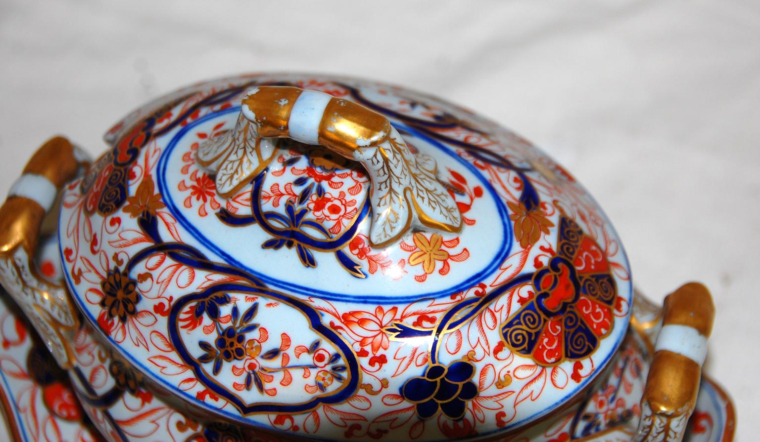 English early 19th century Spode hand painted ironstone sauce tureen and underliner. This small tureen would have been used for gravies or other sauces. It is totally free hand painted with twining leaves and flowers in blue and rust, highlighted