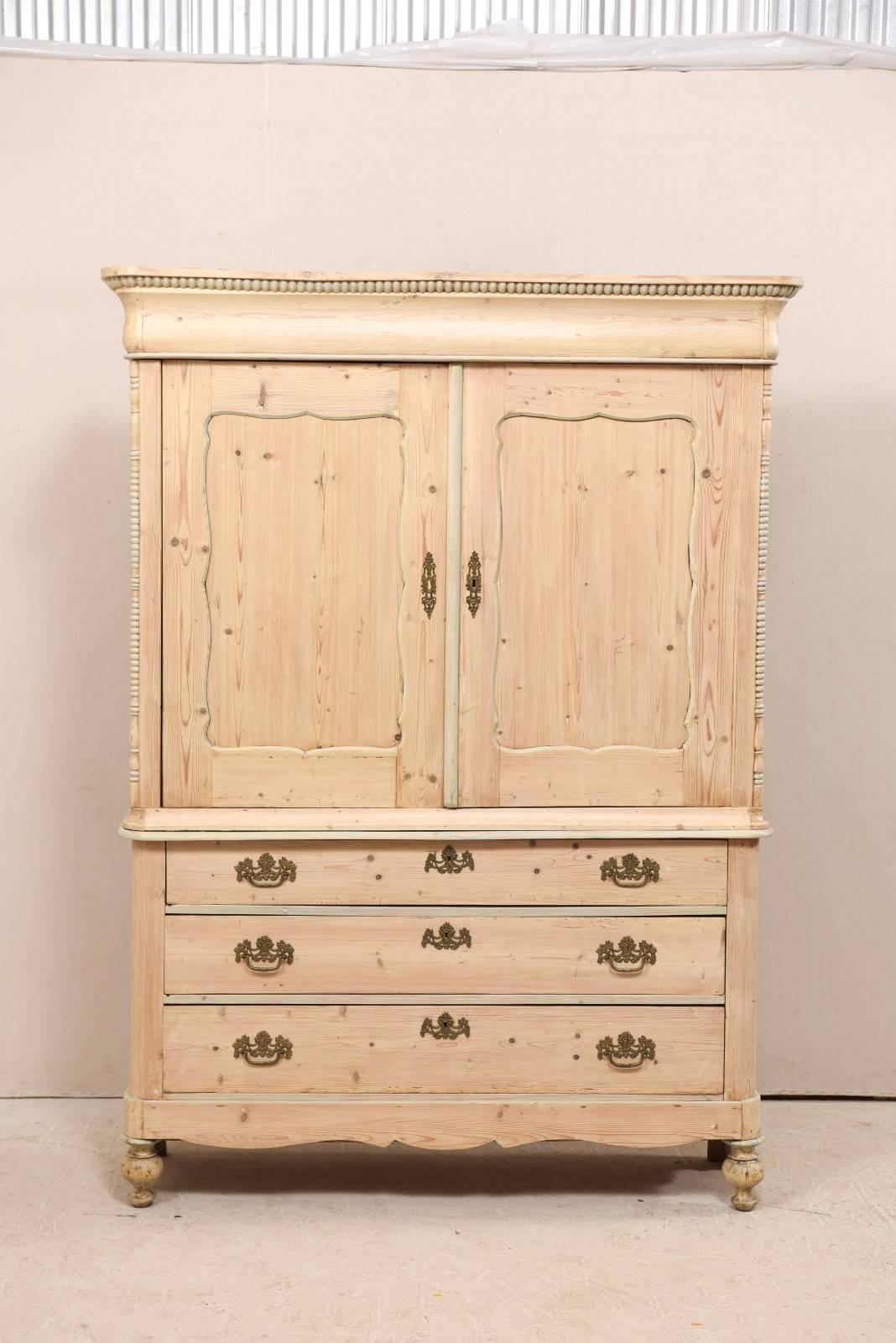 An English tall storage or TV cabinet from the early 20th century. This antique English cabinet features a beautifully curved with flat top cornice which is accented with dentil freize, carved beaded trim flanking each upper side of the cabinet, a