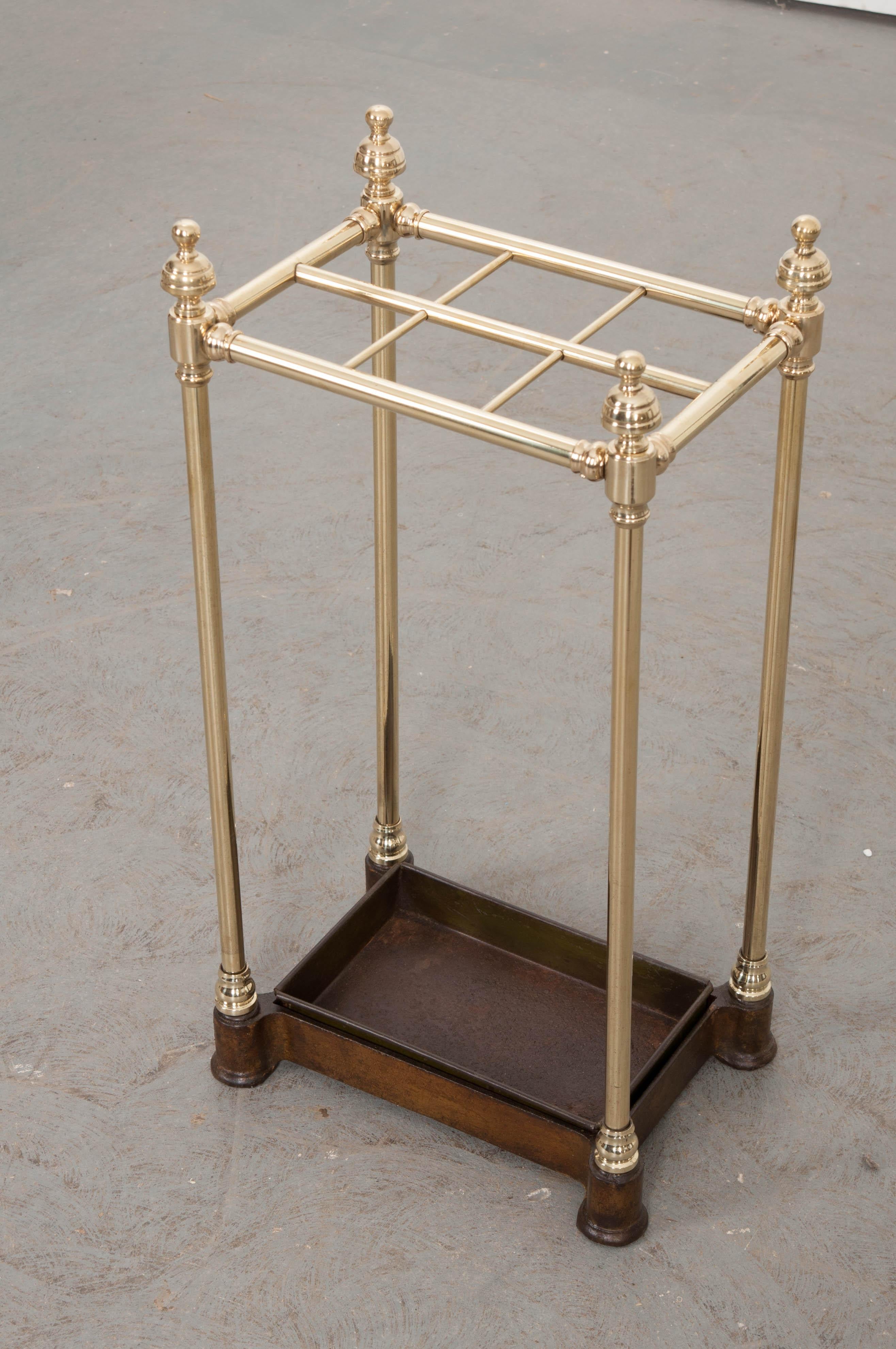 After trekking through the elements, leave your umbrella by the door in this polished brass umbrella stand made in England, circa 1900. The antique has spaces for up to six umbrellas or parasols. The upright supports are topped with decorative brass