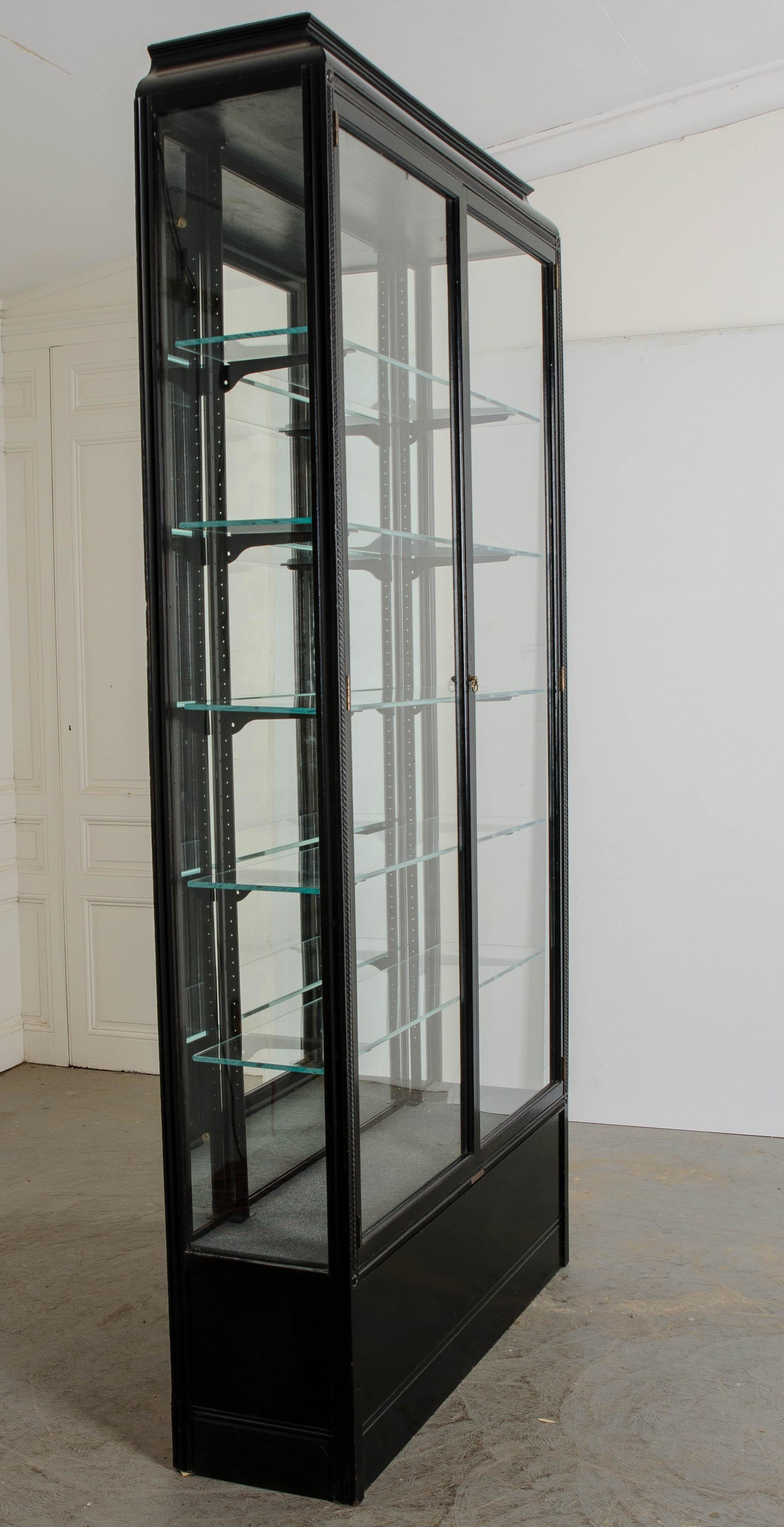 A tall, dark and handsome English vitrine, made in London, circa 1930 by E. Pollard & Co. Ltd.

This exceptional display case is a sight in and of itself! It is finished in a very smart ebonized black lacquer. The case piece has five shelves, made