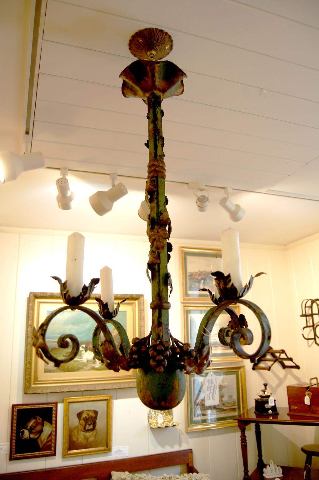 English wrought iron four arm chandelier with entwining grape vines, leaves and grapes. The original painted patination remains - green with gold highlights to the grape motifs. It has been electrified in the past but for the past several decades it