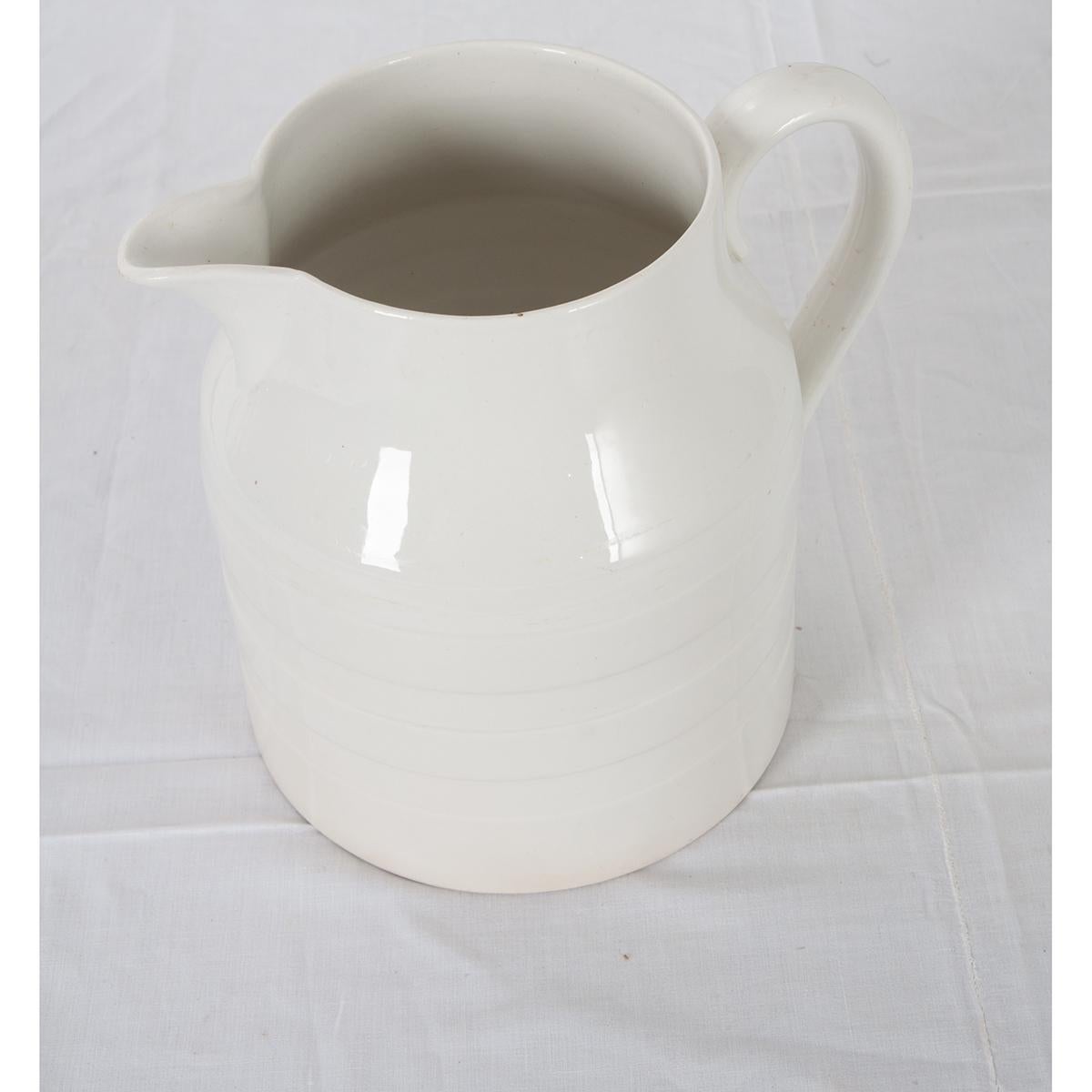 A wonderful early 20th century white ironstone pitcher, from Staffordshire, England, circa 1920. Having raised stripes that encircle the vessel, this mono-chromed white pitcher will add a touch of rustic sophistication to any room. Stamped GJ &