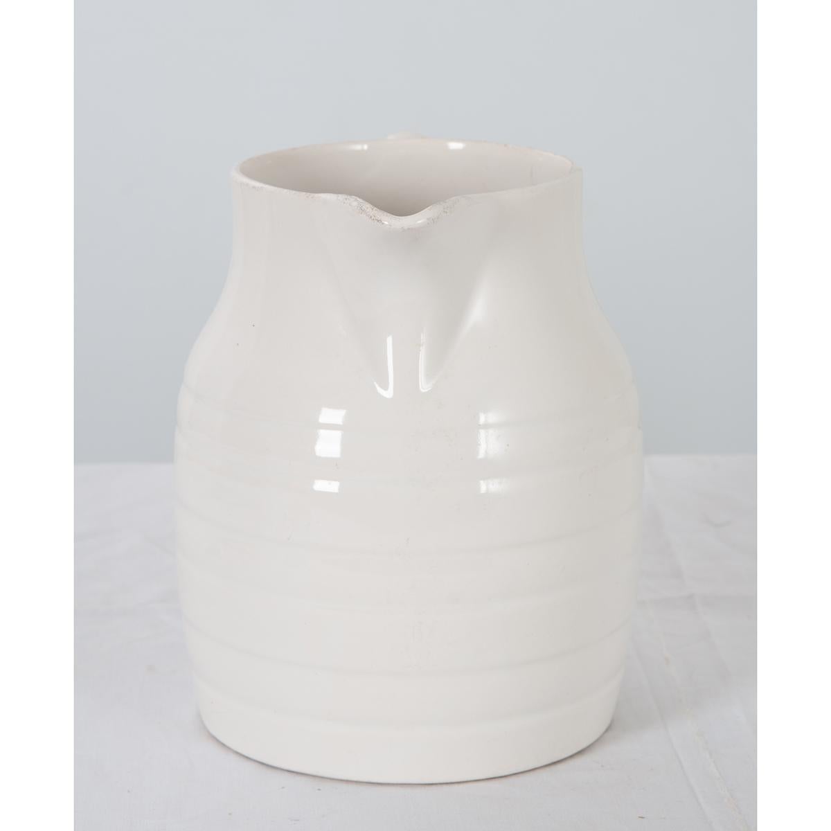 A wonderful early 20th century white ironstone pitcher, from Staffordshire, England, circa 1920. Having raised stripes that encircle the vessel, this mono-chromed white pitcher will add a touch of rustic sophistication to any room. Its loop ear