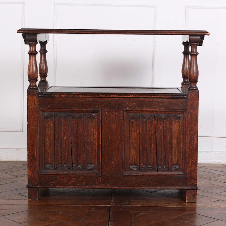 English oak ‘monks’ bench with linen-fold carved fielded panels and baluster-turned arm supports. The back pivots up to rest on the arms, forming a console table if needed; storage under the hinged seat. English, circa 1930

 