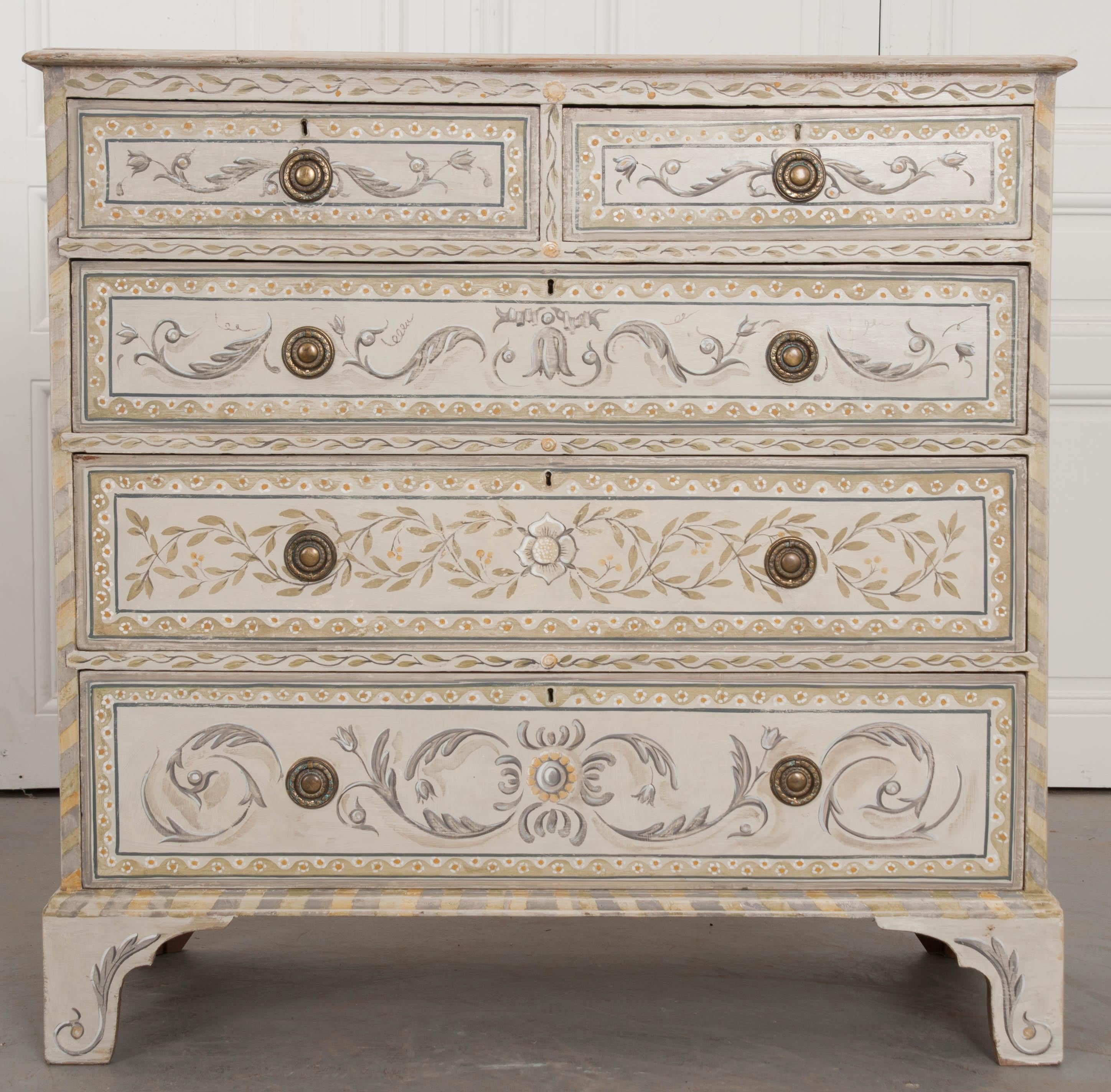 This masterfully painted chest of drawers was made in England, towards the turn of the 20th century. The five-drawer chest has a Classic, Georgian silhouette and has been painted with great attention paid to detail. Scrolled acanthus and leafy
