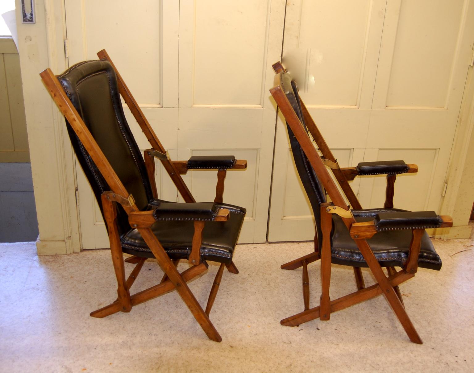 English pair of walnut campaign or deck chairs upholstered in black leather with adjustable backs. These folding chairs are adjustable so they can be as pictured or in increments can go to almost flat. They adjust in small increments via an