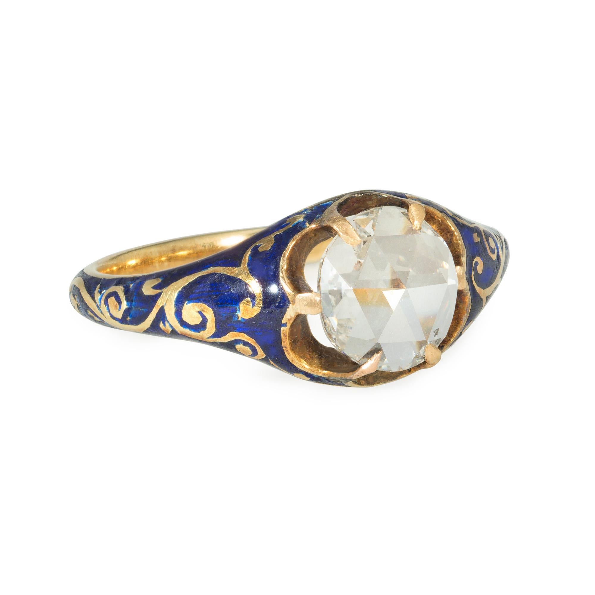 An antique early Victorian gold, diamond, and enamel ring featuring a rose-cut diamond center in a tapering gold mount decorated with a blue enamel foliate pattern, in 15k gold.  England.  Atw diamond 0.47 ct.

Ring may be made smaller by adding a
