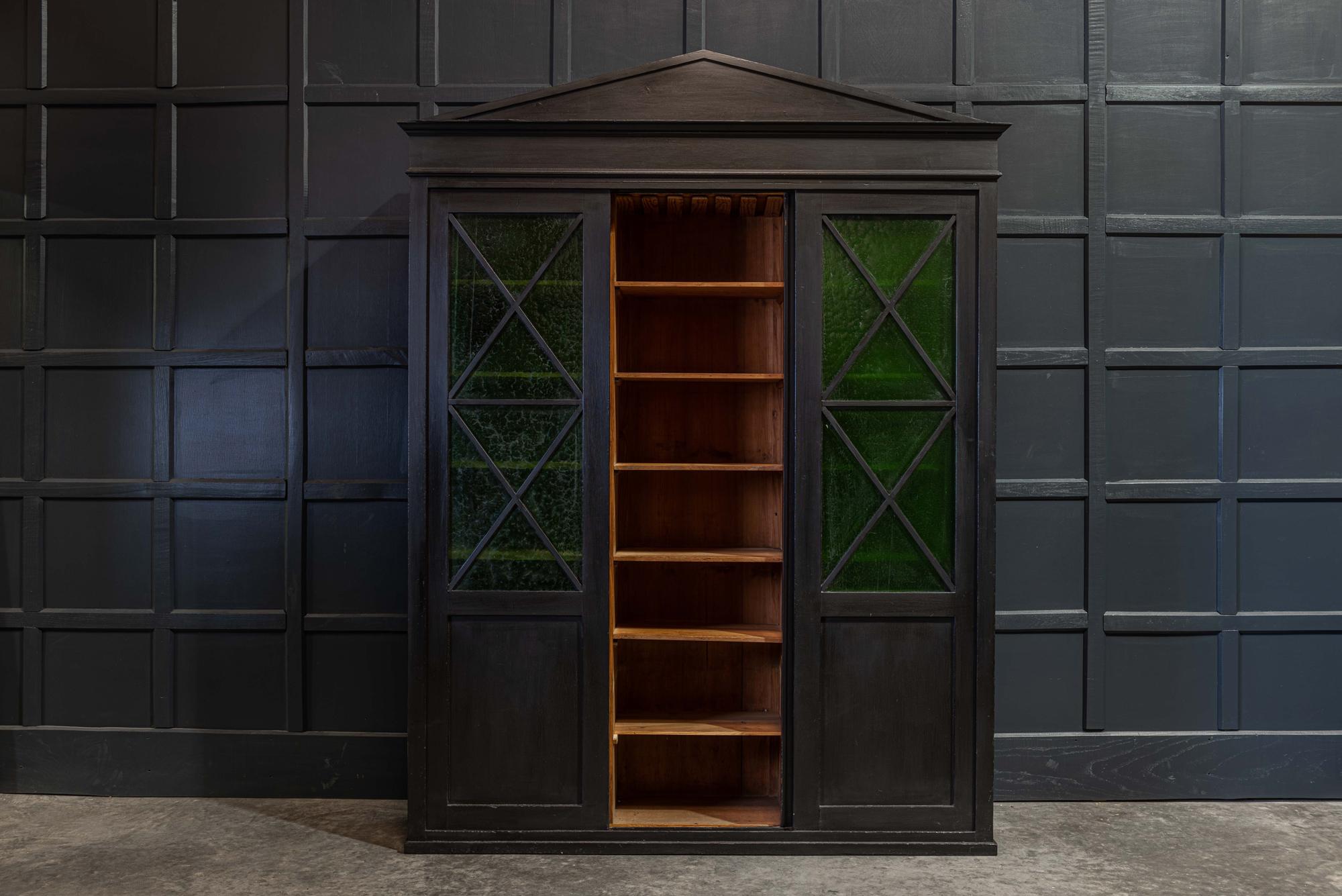 English ebonized architectural glazed bookcase / cabinet,
circa 1900.

A truly interesting and versatile statement piece of furniture with original emerald green hand blown glass panels to the 'X' framed sliding doors. With three tall useful