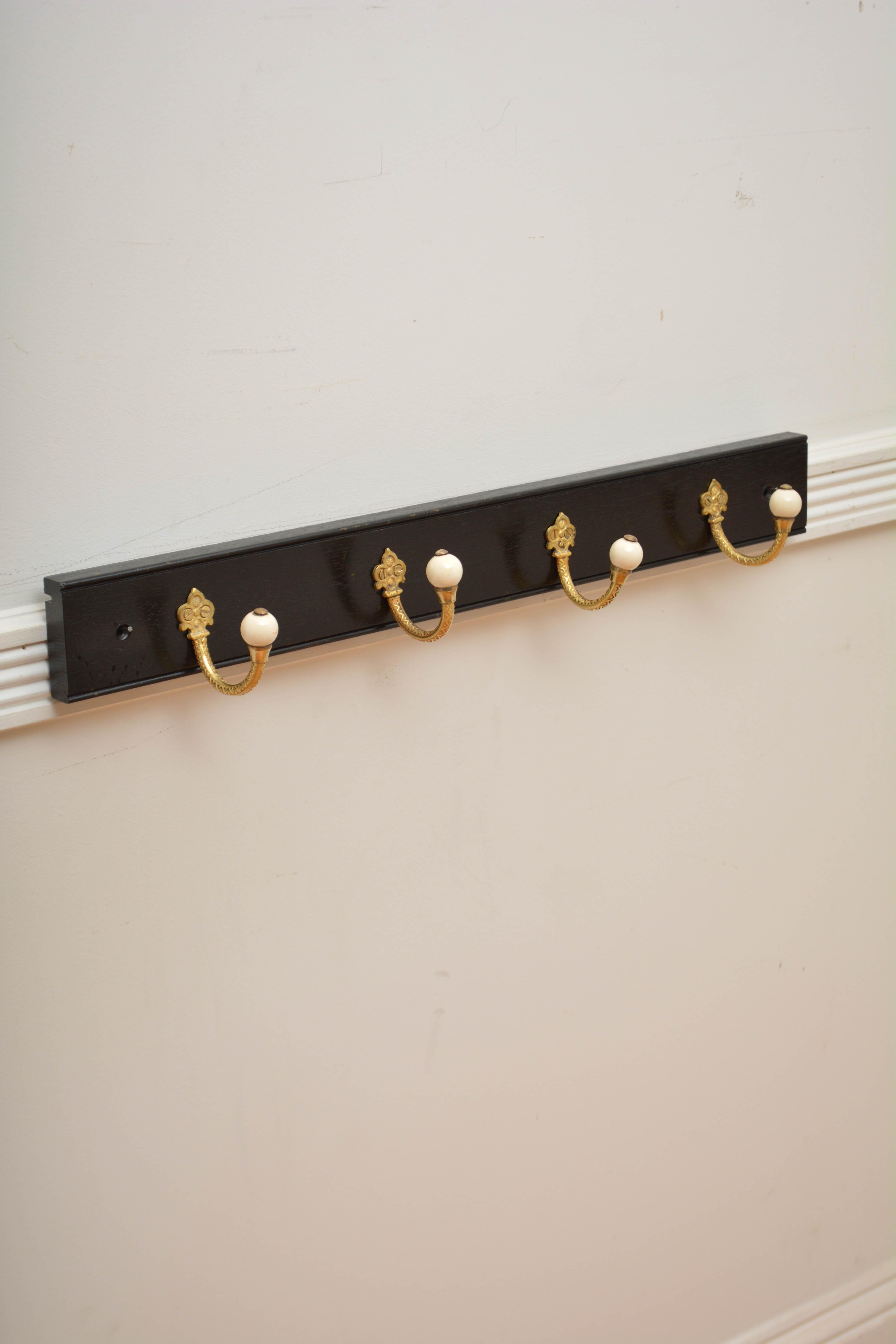 K0311 Stylish and practical brass and ceramic set of four very decorative Victorian coat hooks now on solid mahogany ebonised backing.  Cleaned, polished and ready to place at home. 
H3 1/4