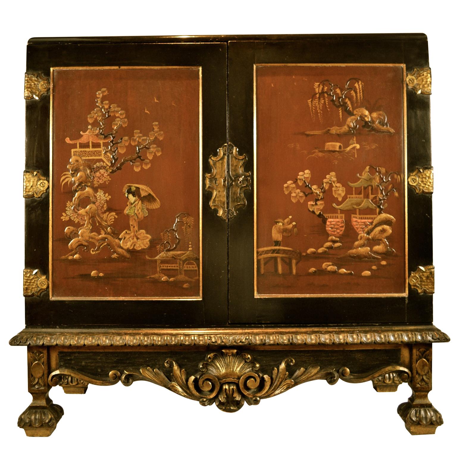 A decorative two-door ebonized oriental lacquer commode in the George II style. The ebonized cabinet sitting on a gilt decorated scroll base, the two door fronts with gilt metal oriental hinges are painted in red lacquer with embossed with Japanese
