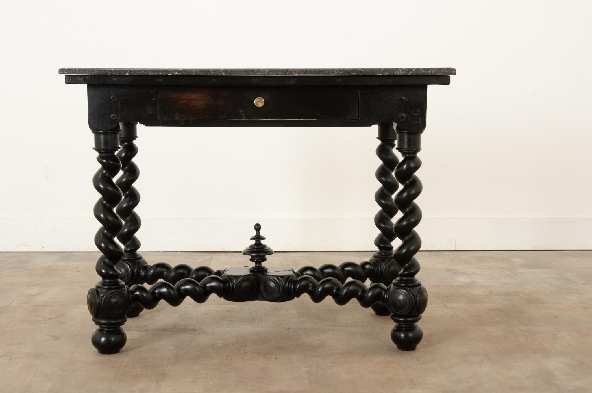 A splendid English ebonized table, made in the 19th century in the Carolean/Restoration style of Charles II, with a more recent stone top. The rectangular top is of a gorgeous marble that showcases veining that runs across its whole surface. A