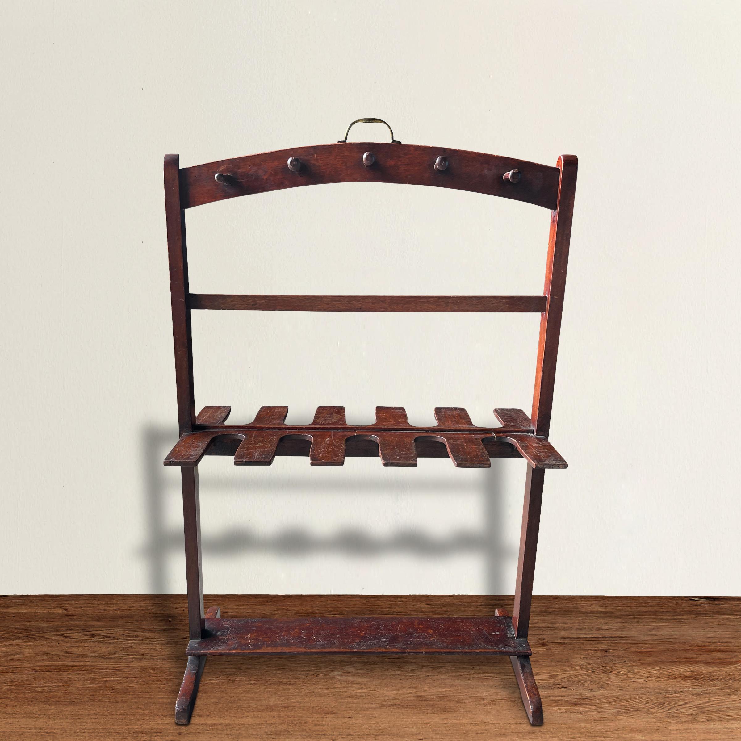 A wonderful early 20th century English Edwardian mahogany boot rack with enough space for five pairs of boots, and ten pegs traditionally used for holding horse whips but can perfect for holding hats, purses, and/or umbrellas.