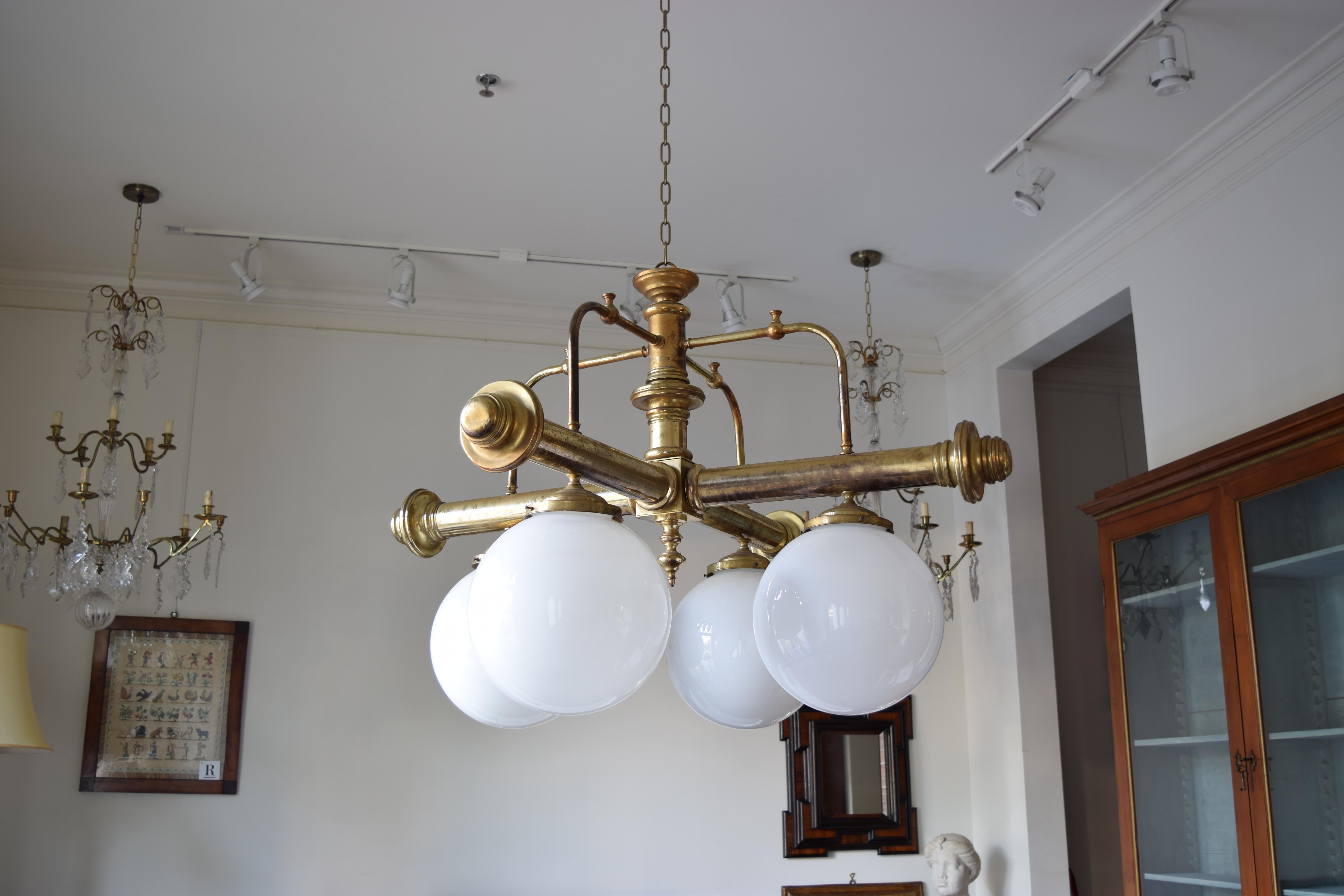 the all brass frame having a central standard and issuing four large arms with original hanging glass globes on each