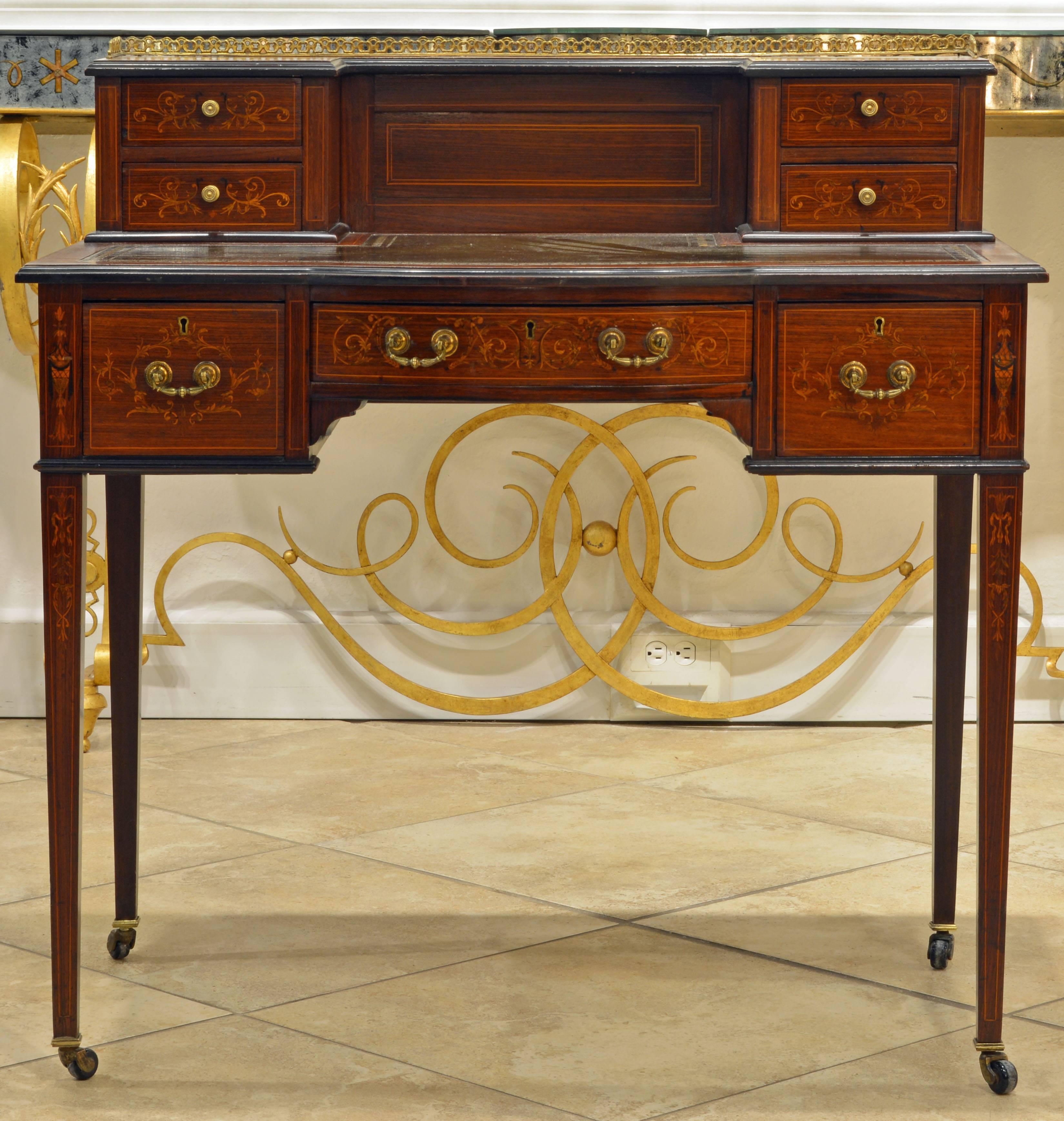 A lovely Carlton House style writing desk with elaborate overall inlay, gilt tooled leather writing surface and bronze gallery. It evokes Downton Abbey associations.