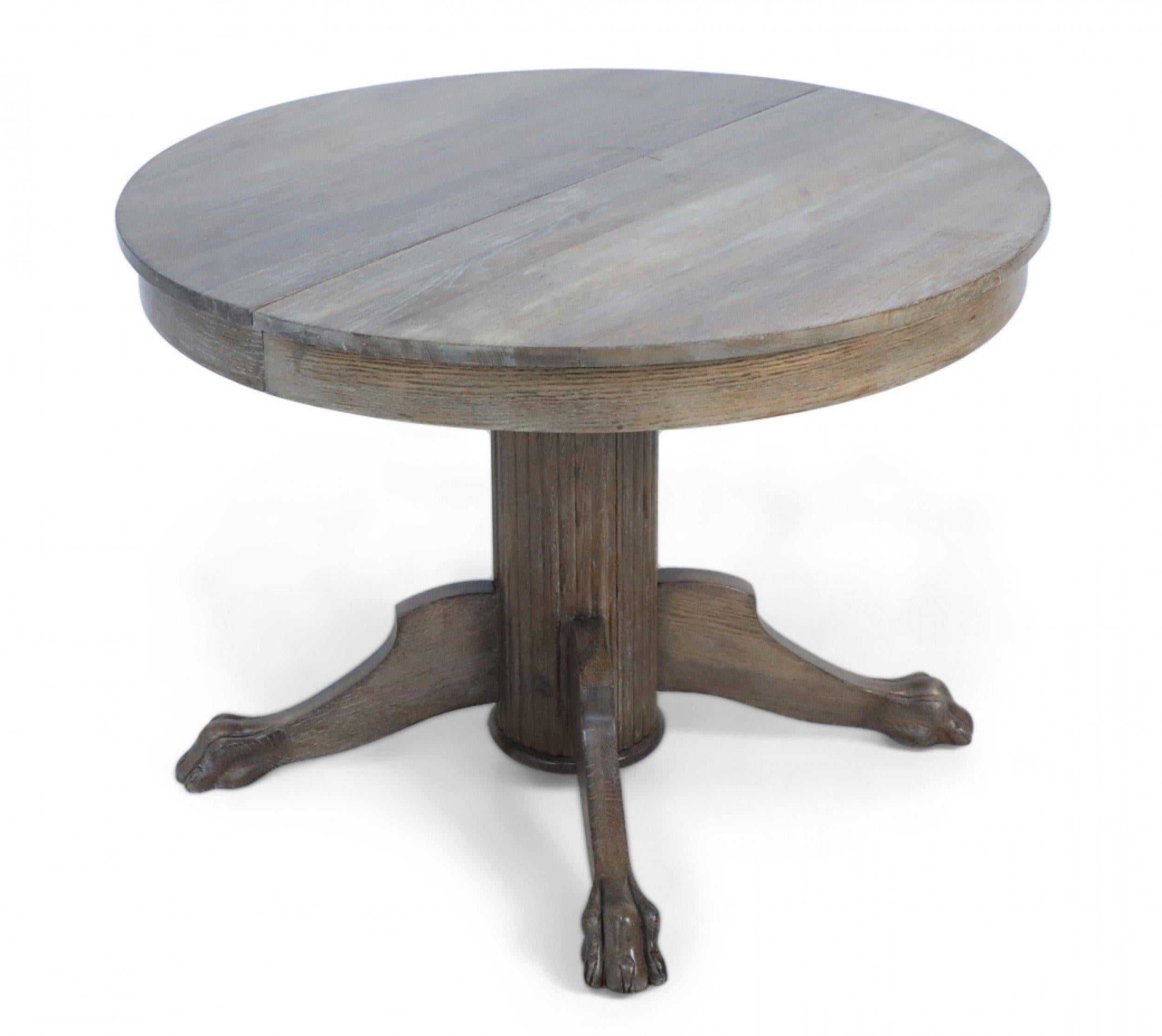 English Edwardian cerused oak dining / center table with a circular top resting on a fluted pedestal base with three claw feet. (two 23.5