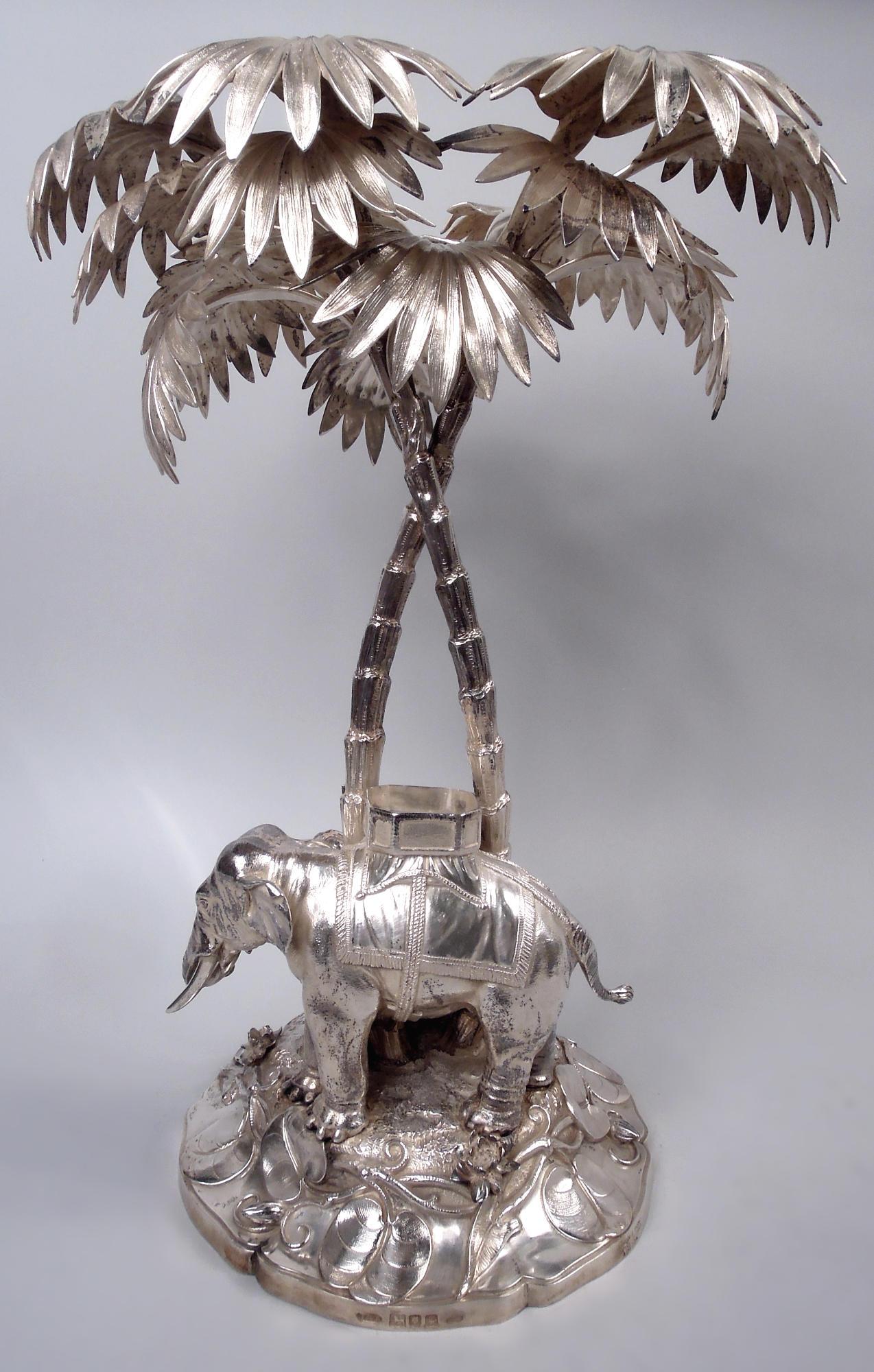 Edwardian sterling silver exotic centerpiece. Made by Dobson & Sons in London in 1902. Entwined palm trees shade an elephant, whose trunk reaches out to the food offered by one of two turbaned men. The howdah awaits a pith-helmeted sahib to command