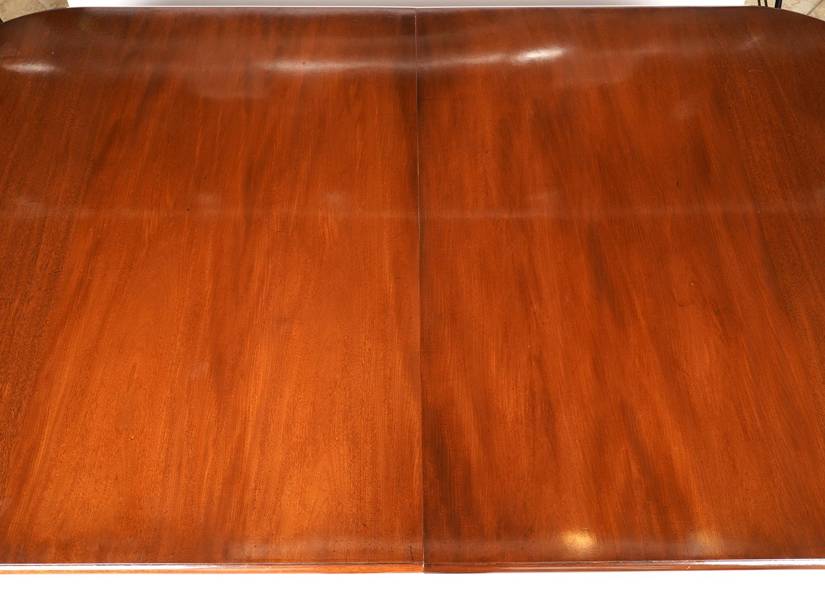 This exceptional Edwardian mahogany dining table comes with three leaves bringing the total length to 160 inches. The table features a rounded end polished top with moulded edge above a frieze resting on bronze mounted circular tapering legs ending