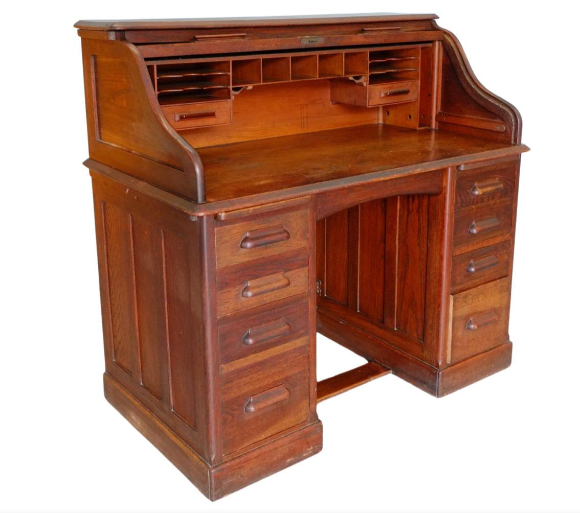 Beautiful English Edwardian double pedestal, roll top oak desk. Handsomely made by ‘HLL’ Harris Lebus, London ‘Entirely English Make’. Classic English solid oak desk from the early 1900's. Fitted with so many drawers, writing trays and pigeon holes