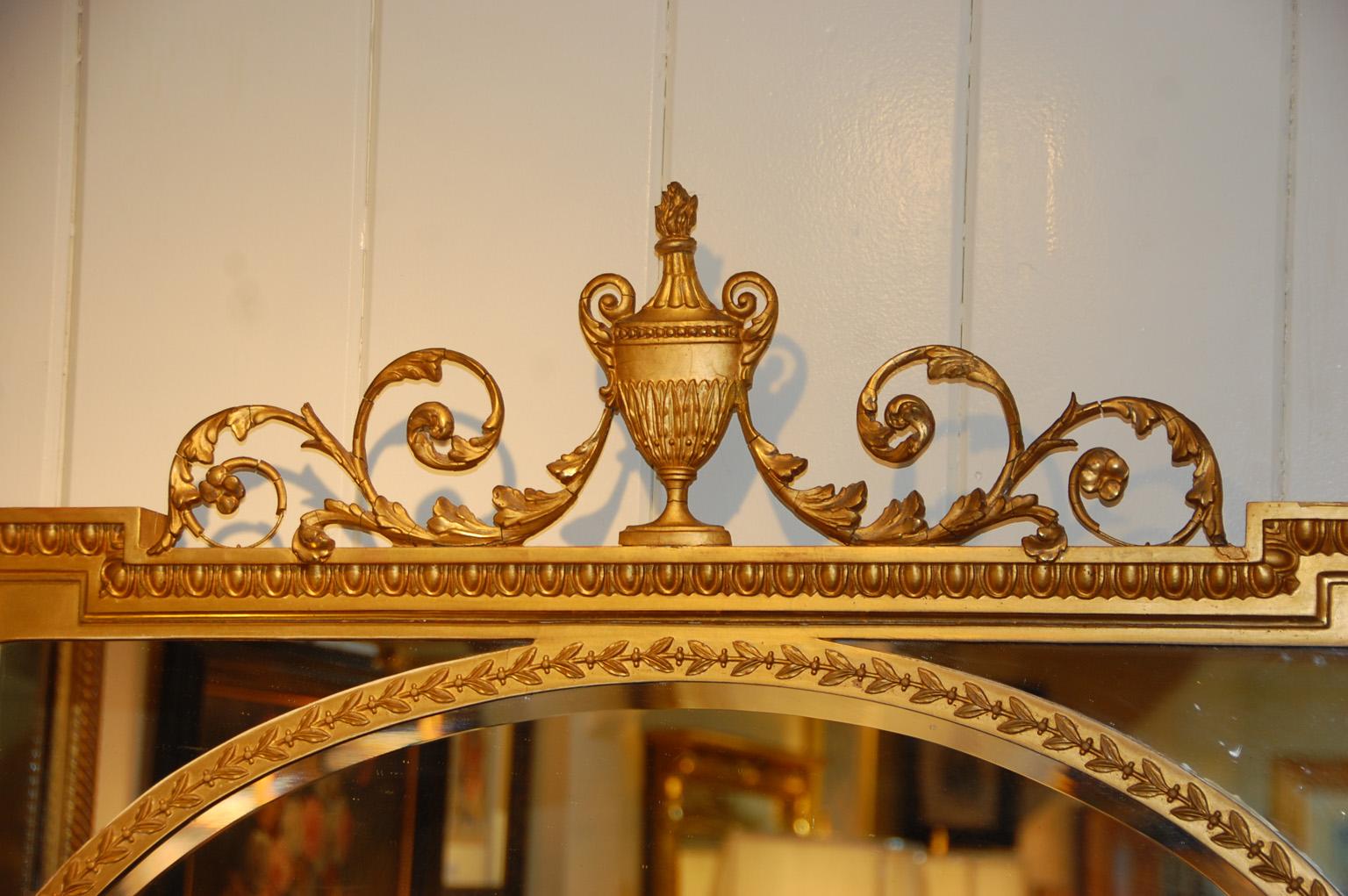 Miroir anglais édouardien en or avec urne et feuilles rampantes surmontant le cadre rectangulaire. Ce miroir inhabituel présente un miroir ovale dans un cadre rectangulaire, créant une scène dans une scène plus grande. Le délicat tracé qui émane de