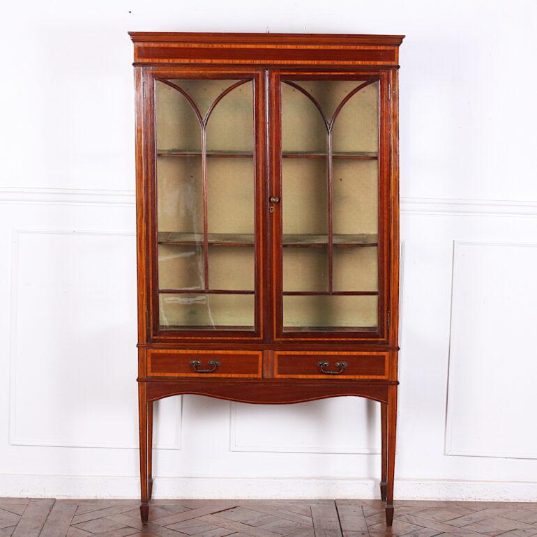 Elegant English-made Edwardian Sheraton style inlaid china cabinet or vitrine in mahogany with satinwood banding to the drawers and case, and standing on square-tapering legs with spade feet. Two drawers with hand-cut dovetail joinery and retaining