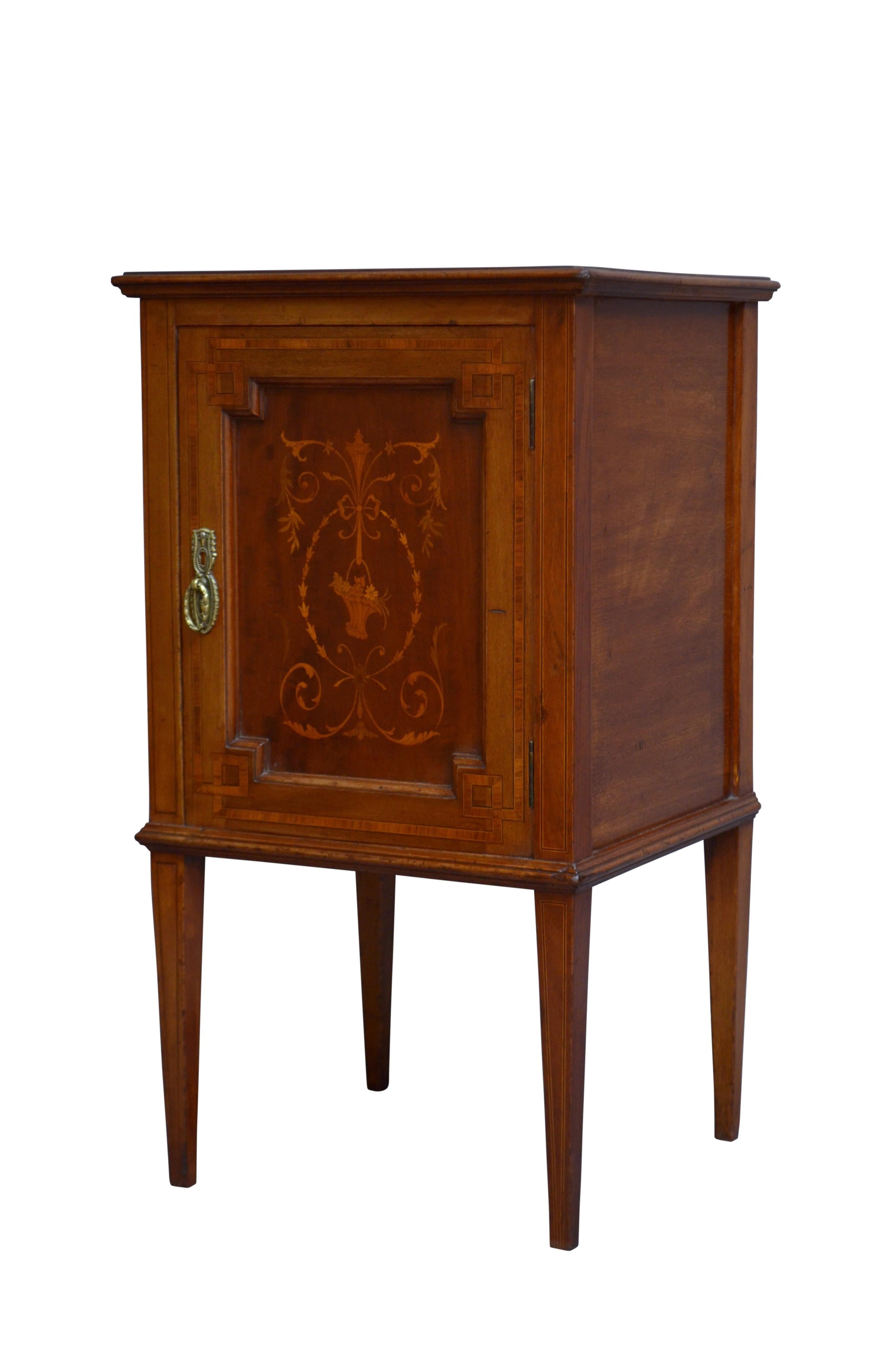 K0302  Attractive English Edwardian bedside cupboard in mahogany, having figured mahogany and inlaid top with moulded edge above satinwood crossbanded and inlaid panelled door fitted with original brass handles, all standing on inlaid tapered legs.