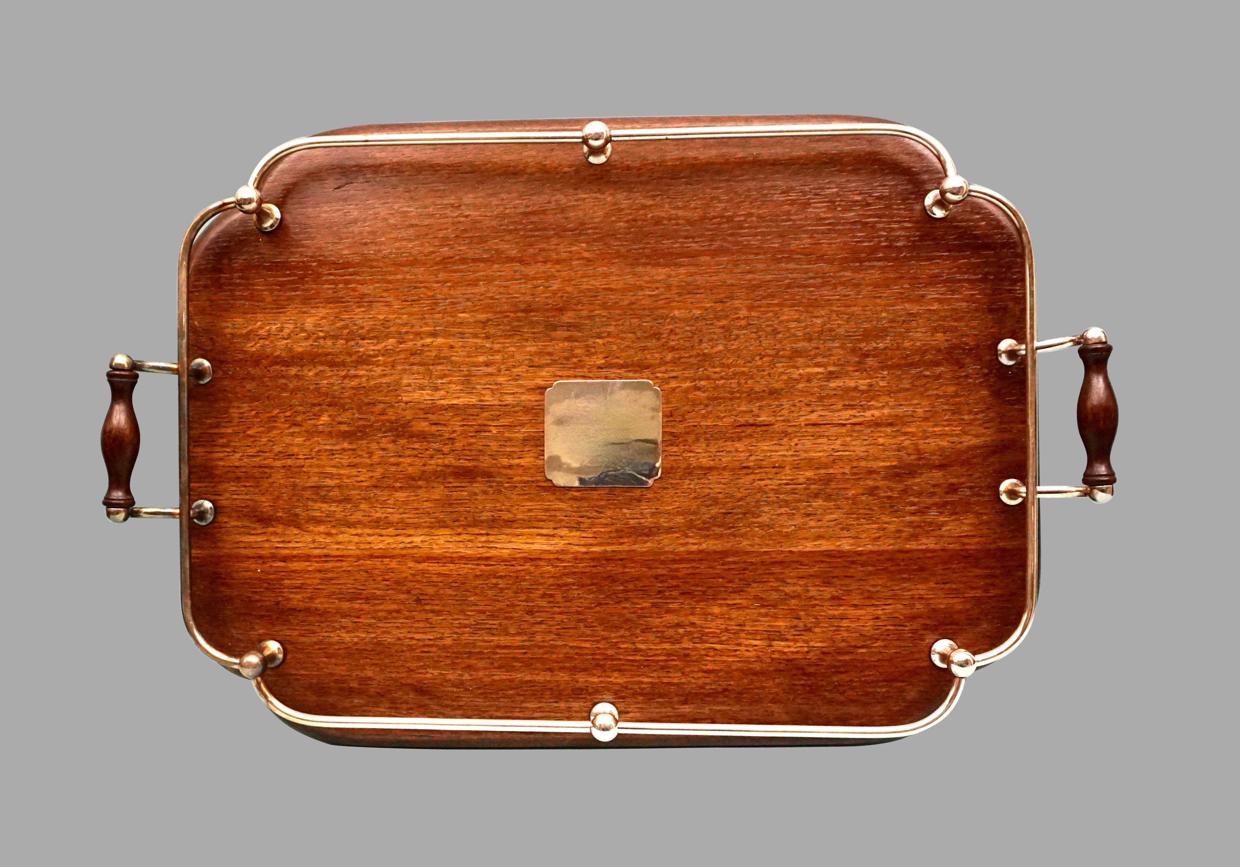 An attractive and utilitarian English mahogany serving tray, centered with an inset silver plated panel, the perimeter fitted with a silver plated gallery. circa 1920. Restored.
