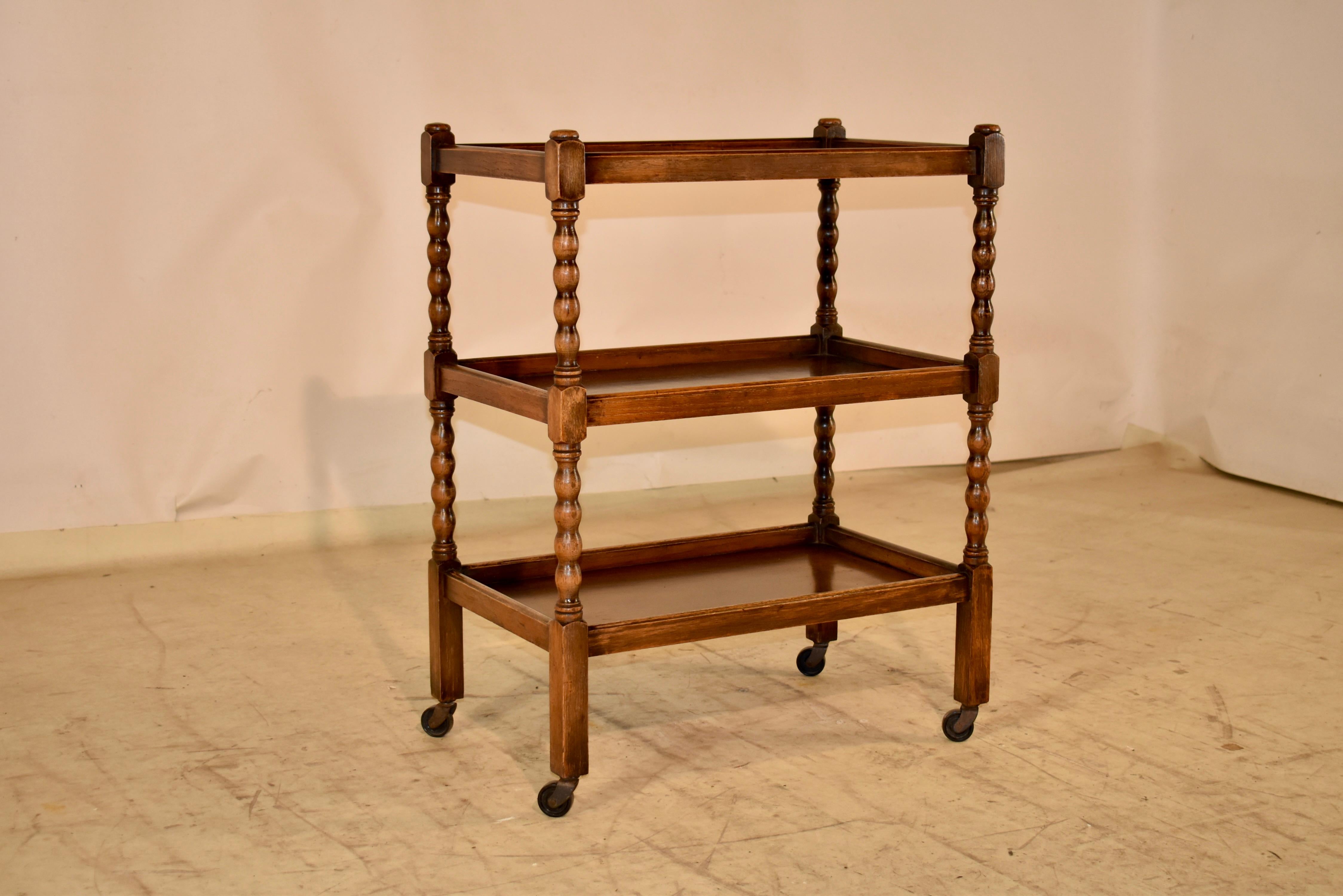 Circa 1900 English Edwardian drinks cart made from oak.  The cart has three shelves, all with galleries.  The shelves are separated by hand turned spool legs, and are supported on what appear to be the original casters.  These are great for use as