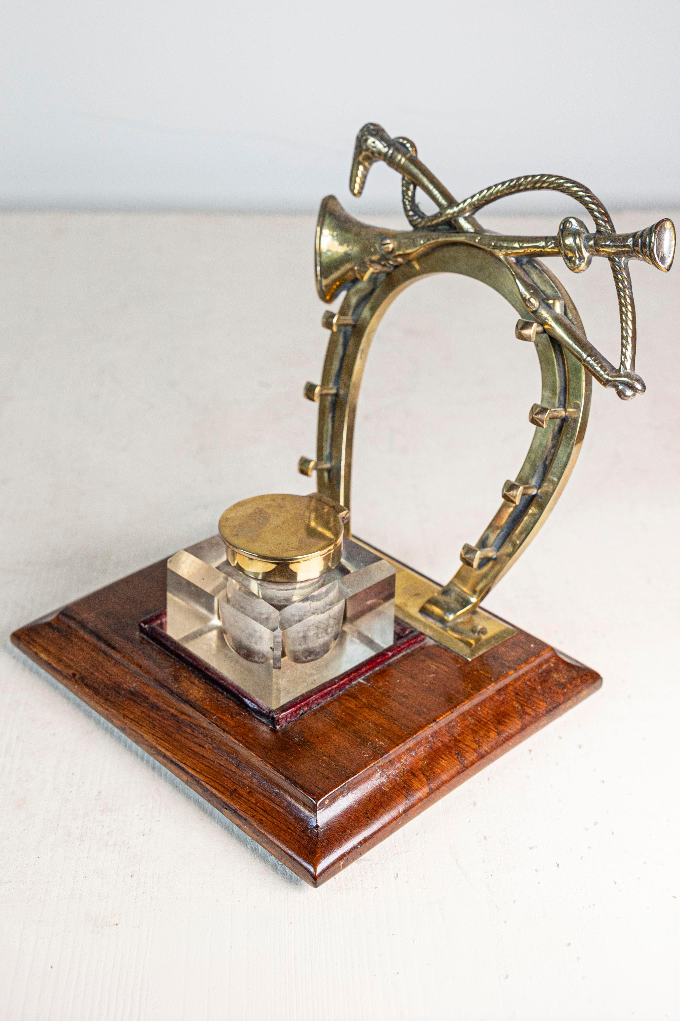 Calamaio inglese di epoca edoardiana dei primi del Novecento, con motivi equestri in ottone e base in legno. Nato nei primi anni del regno di Edoardo VII, figlio della Regina Vittoria, questo elegante pezzo presenta un calamaio centrale, accentuato