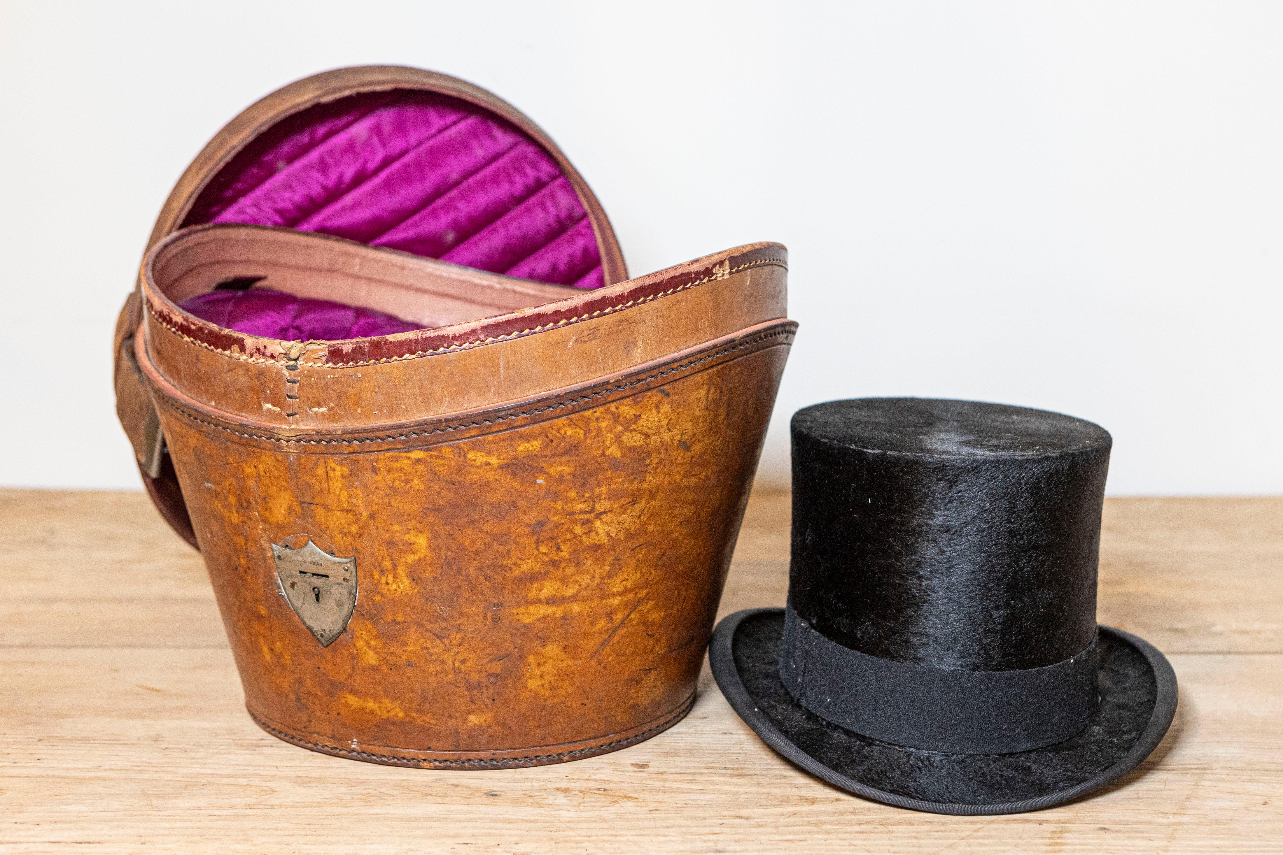 An English Edwardian period leather hat box from the early 20th century created by Austin Reed LTD, with top hat. Created in England during the early years of the 20th century by fashion retailer Austin Reed, this leather hat box features a tapering
