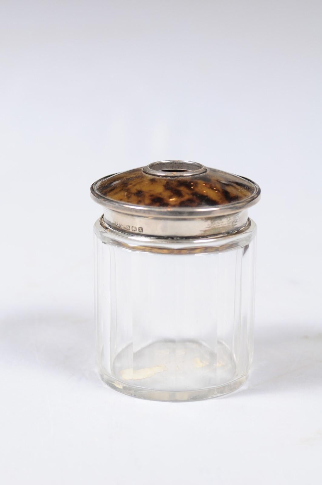 An English Edwardian period crystal toiletry bottle from the early 20th century with silver accents and conic lid. Born in England during the early years of the 20th century, this delicate toiletry bottle features a crystal body of cylindrical