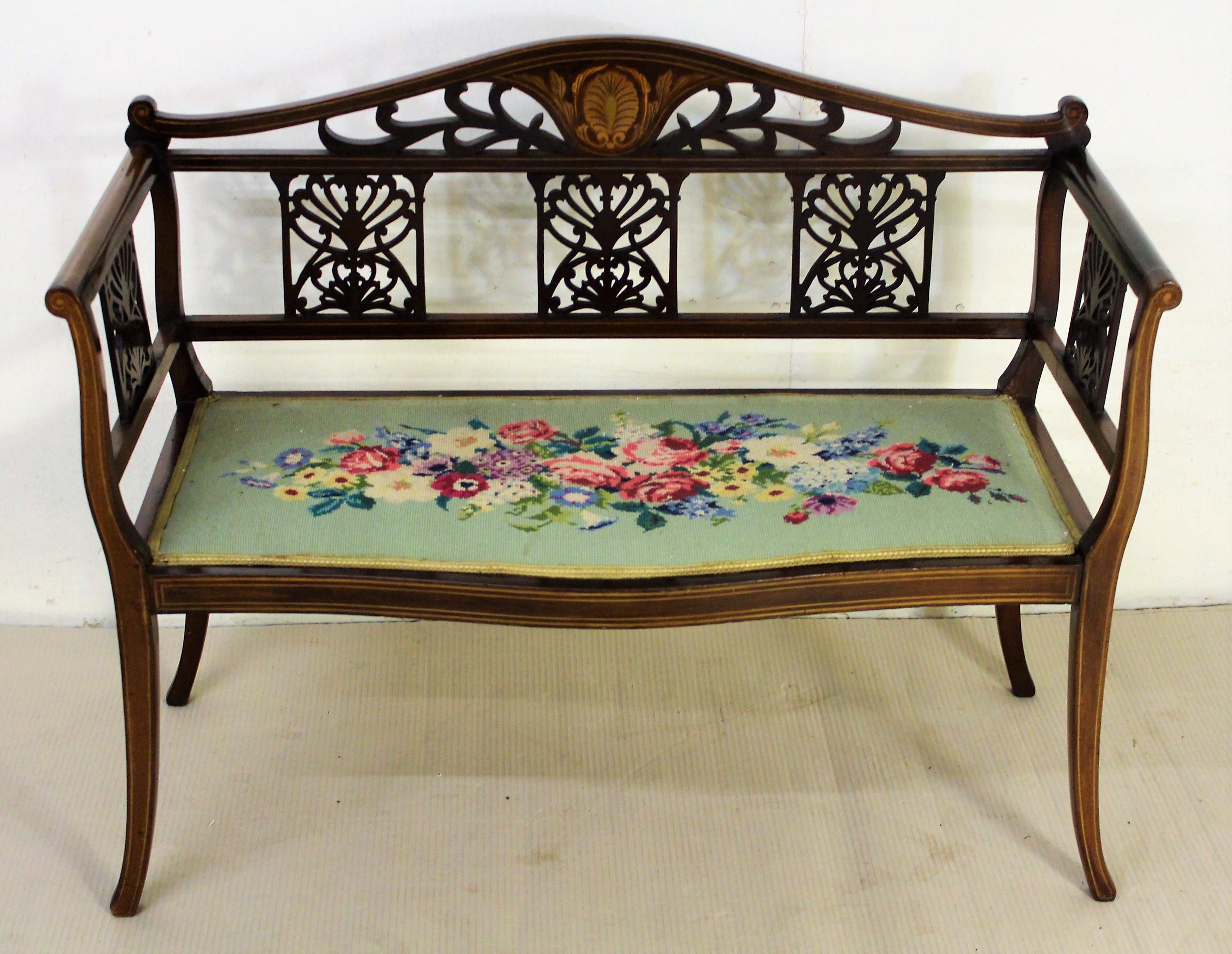 A pretty and refined inlaid mahogany settee, or bench, from the Edwardian period. Well constructed in solid mahogany and decorated with inlaid boxwood stringing throughout. With a central inlaid motif to the back and open fretwork panels to the back