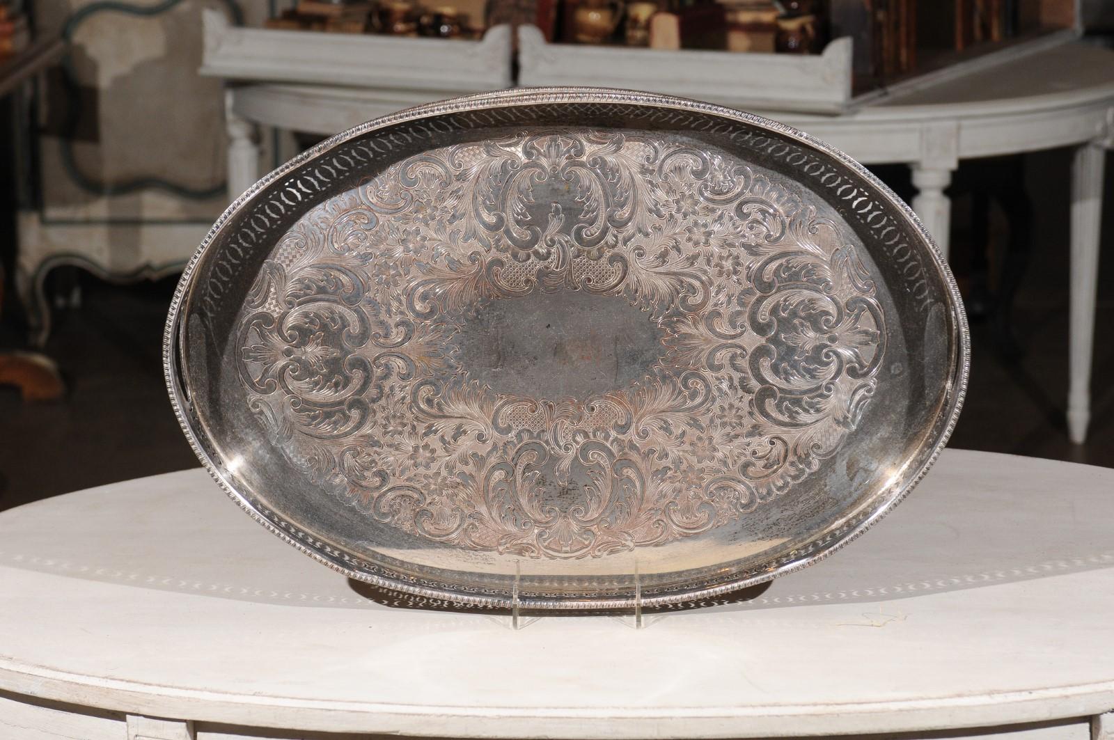 An English Edwardian period silver plated tray from the early 20th century, with pierced motifs, C-scroll design and oxidized patina. Born in England in the early years of King Edward VII's reign, this exquisite silver plated tray features an oval