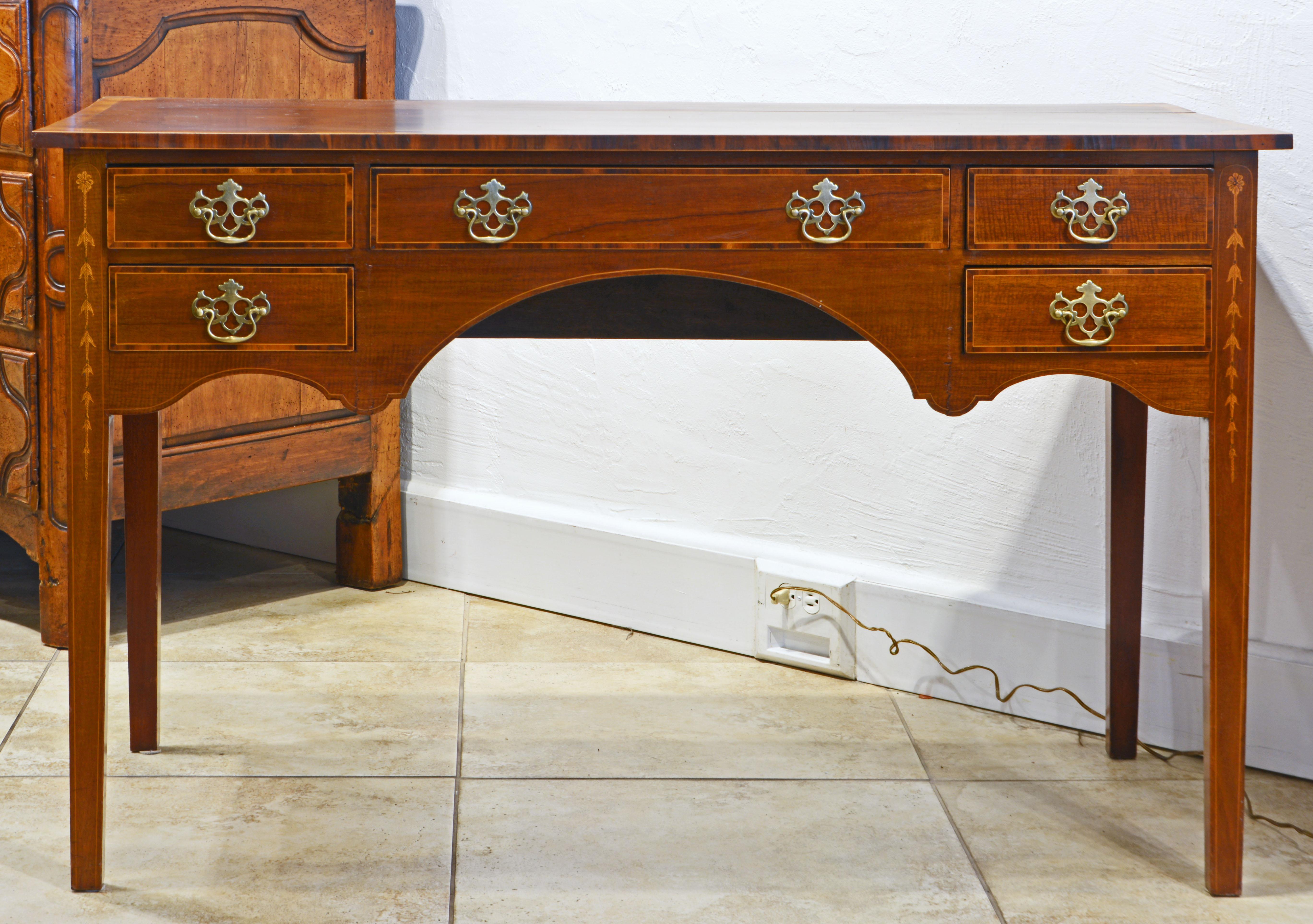 This charming petite size mahogany writing desk features a rosewood banded top accented by satinwood fan corner inlays above five banded and stringed drawers flanked by the front legs with pen worked bell flower inlays. The apron is elegantly shaped