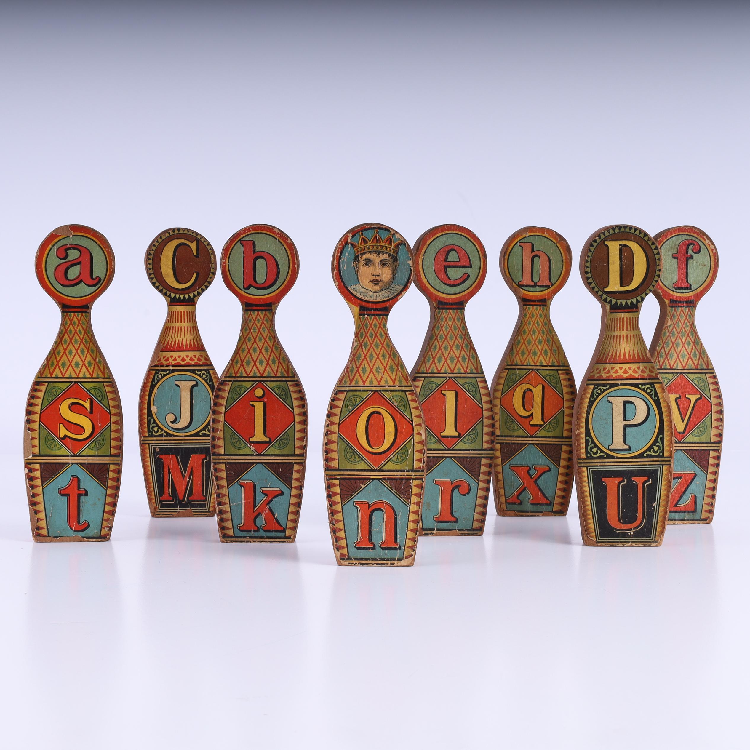 Intriguant groupe de huit pièces de jeu anglaises en bois, en forme de quilles de bowling, recouvertes de papier avec des lettres imprimées décoratives maintenant vieillies à la perfection.
