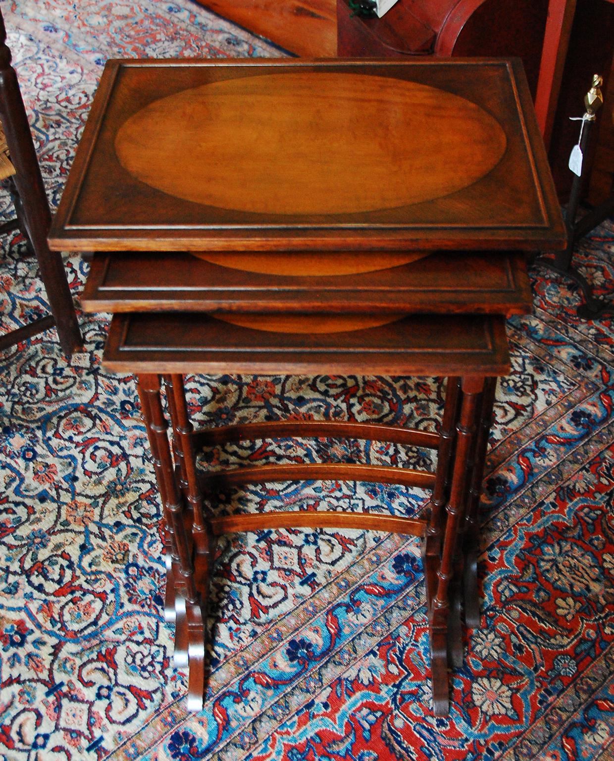 English Edwardian mahogany set of three nesting tables with oval inlays in satinwood, low gallery, delicately turned legs with curved stretchers. These three tables stack together nicely and can be pulled out so one, two or three tables are usable.