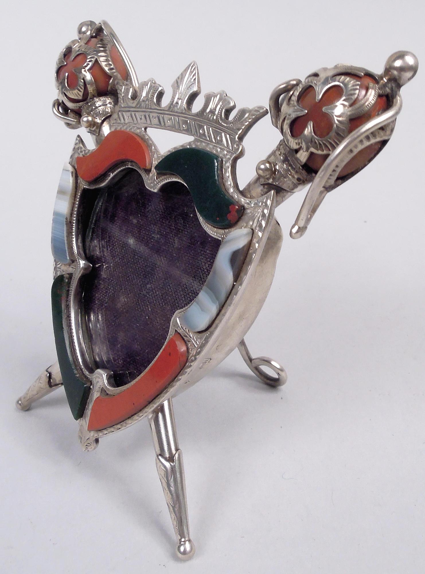 English Edwardian sterling silver and agate picture frame, 1903. Silver armorial surround applied with agate and surmounted by coronet. Crisscrossing standards with agate terminals. With glass and hinged wire easel support. Fully marked including