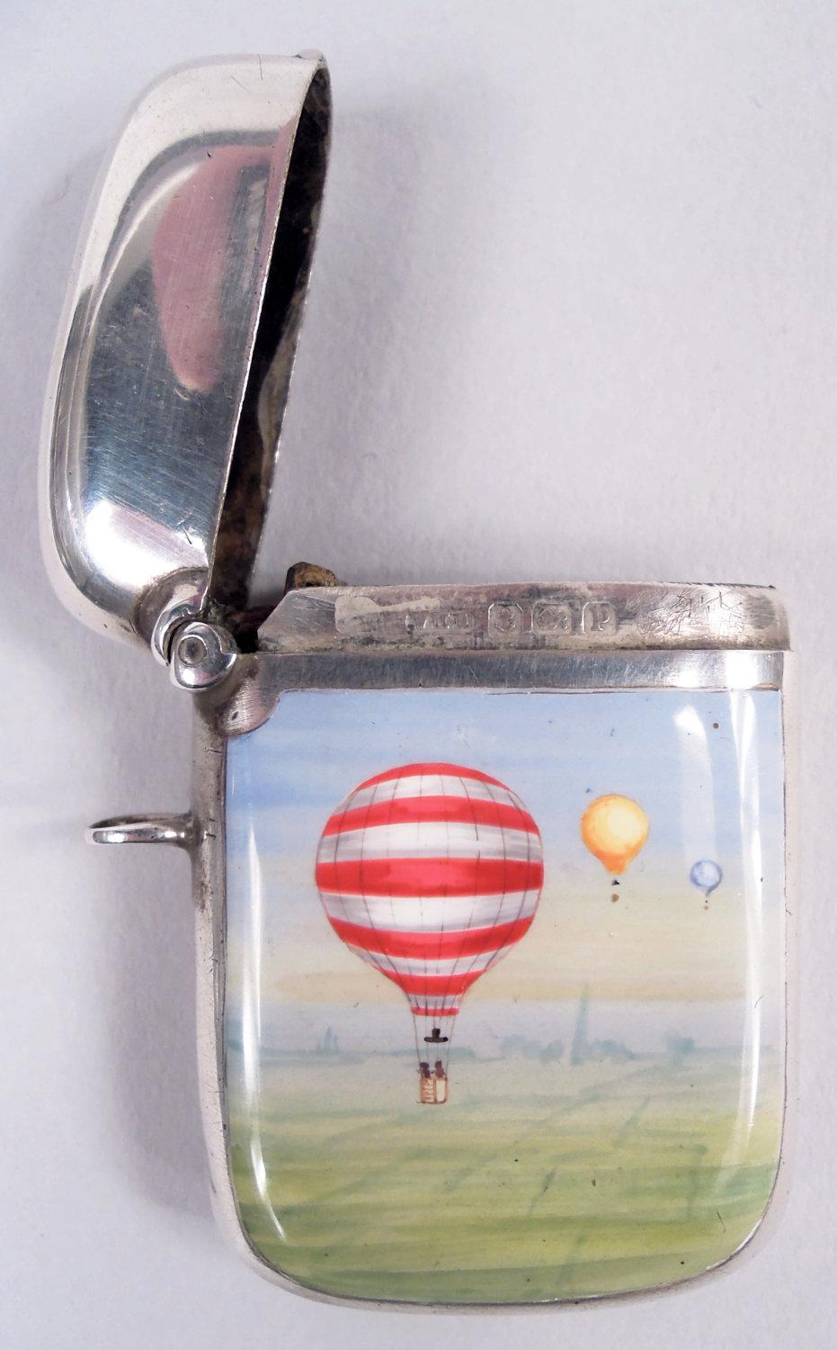Caja de cerillas de plata de ley y esmalte Jorge V. Fabricado por William Hair Haseler en Birmingham en 1914. Tapa abatible, anilla fija y cerradura inferior. Escena esmaltada: Globos flotando sobre una campiña bucólica sin ningún indicio de lo que