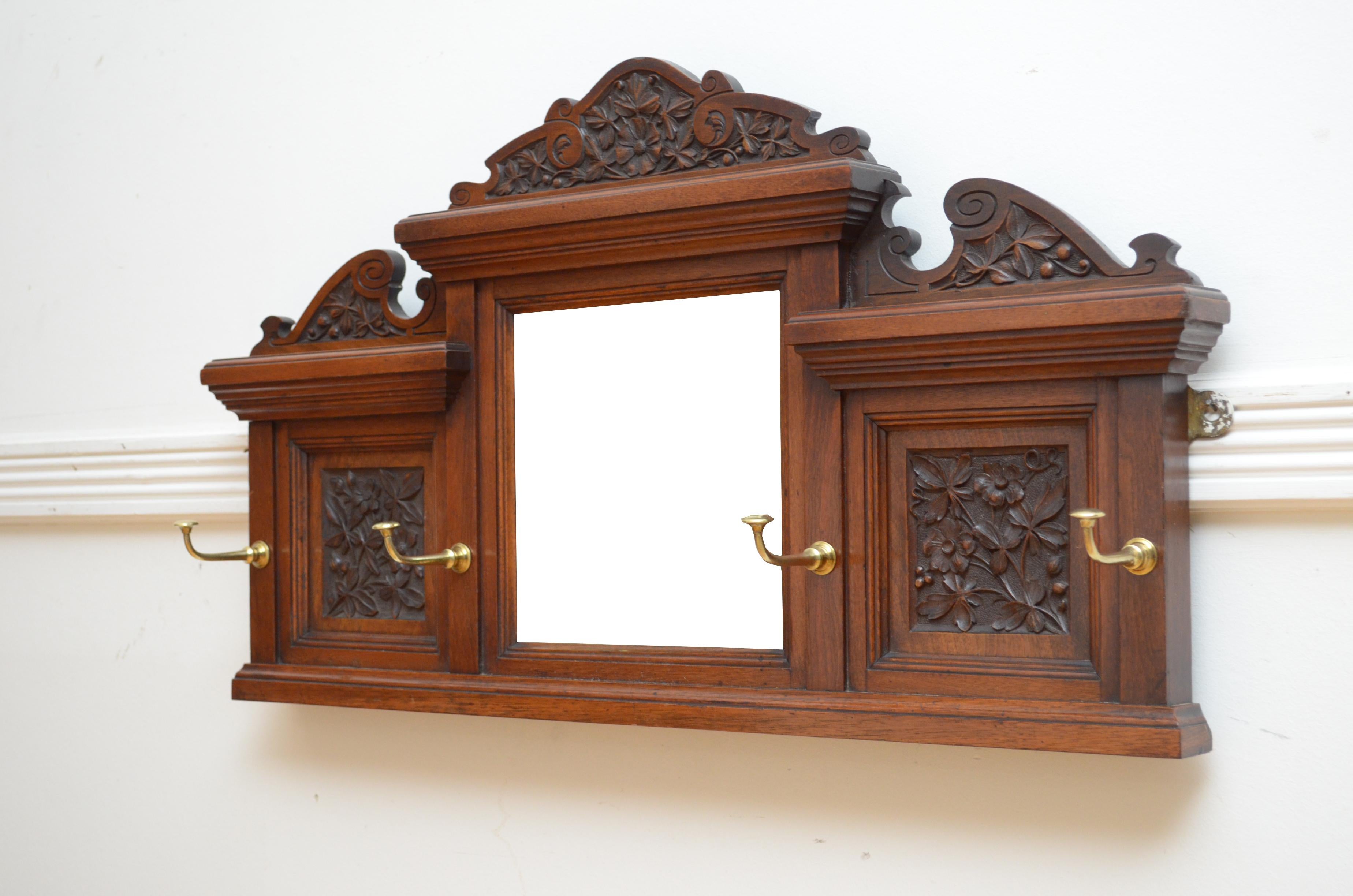 P0294 Elegante appendiabiti inglese edoardiano in noce, con tripla alzata finemente intagliata sopra l'originale specchio a bordo smussato affiancato da pannelli decorativi floreali intagliati, il tutto dotato di quattro ganci sporgenti in ottone.