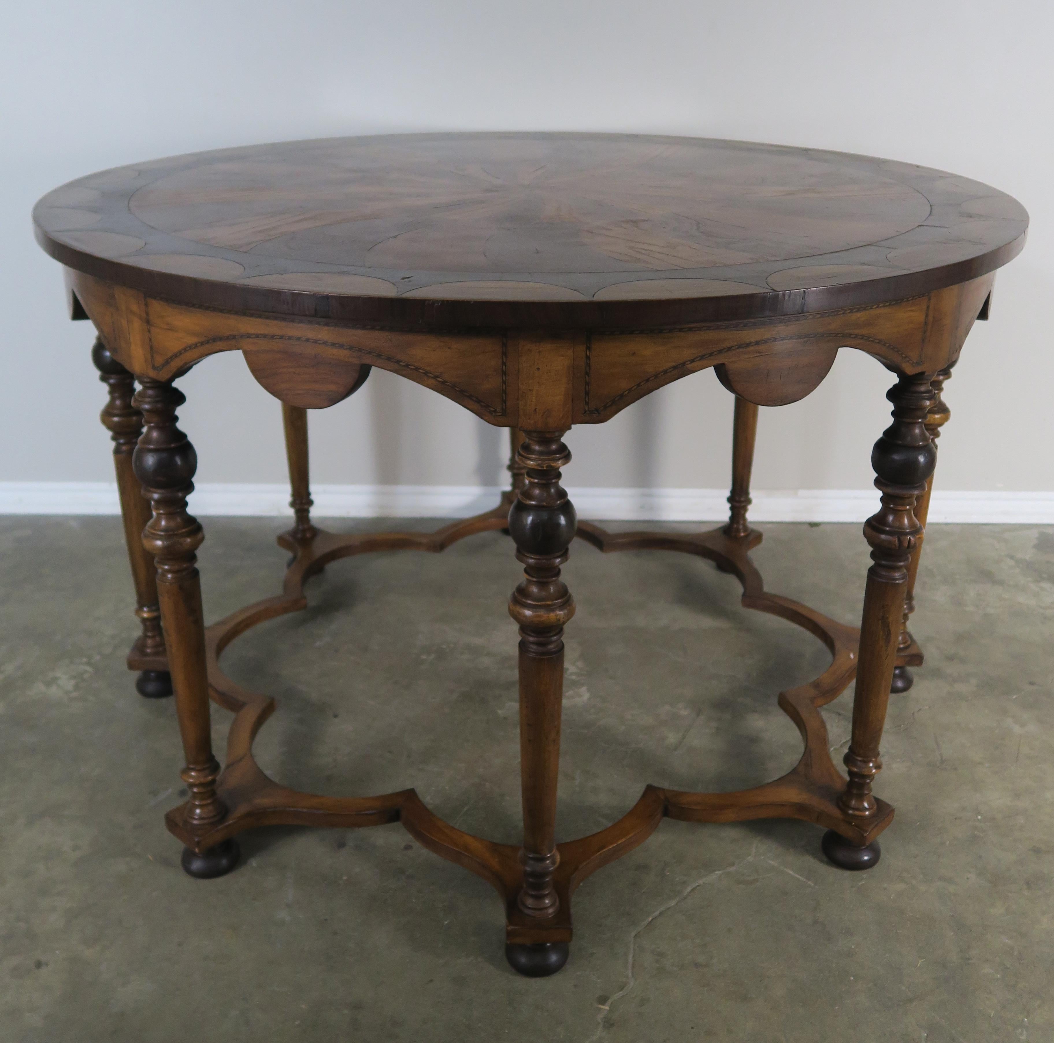 Round eight legged inlaid table with star-shaped stretcher that attaches all eight legs together. The table is made from a combination of walnut, mahogany, ebony, and elmwood carefully inlaid to create a beautiful design.