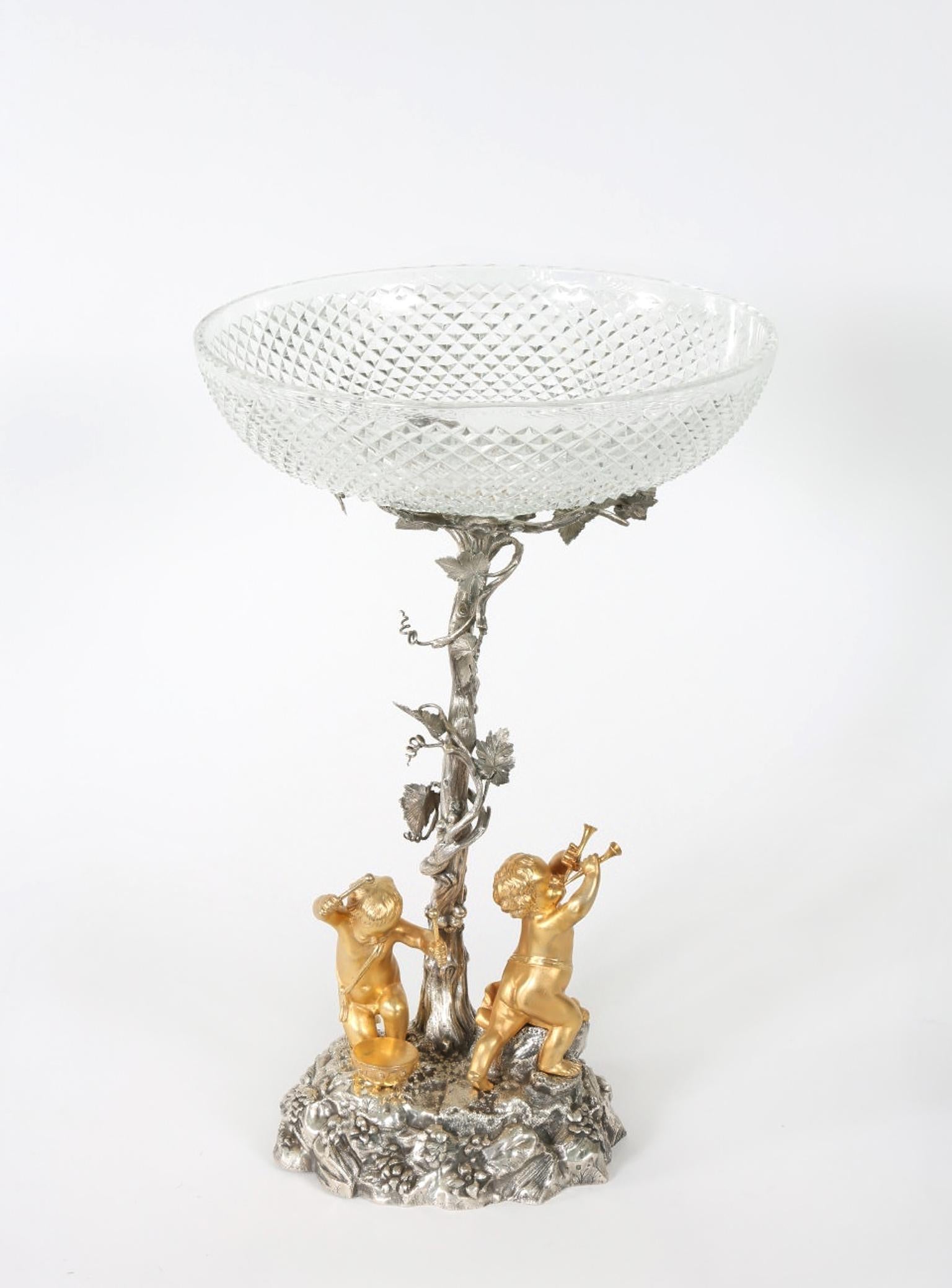 English Elkington silver plated / cut crystal tableware centerpiece with two standing putti playing instruments at the foot of an ivy wrapped tree. The piece is in great antique condition . maker's mark undersigned . The piece stand about 16