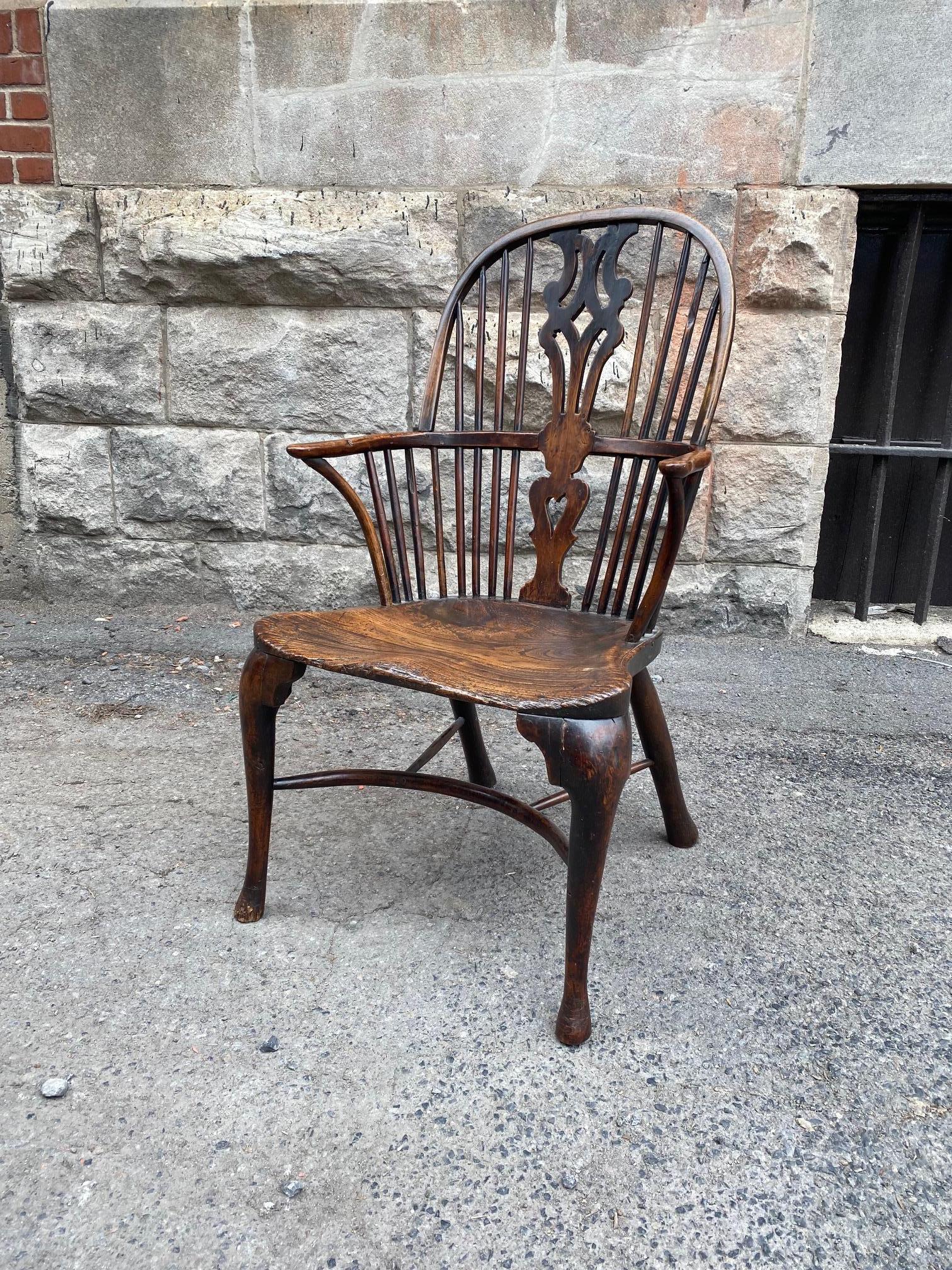 18th century high hoop back Windsor arm chair, pattern over shaped elm seat and joined by crinoline stretcher, the whole possessing good rich nutty color.