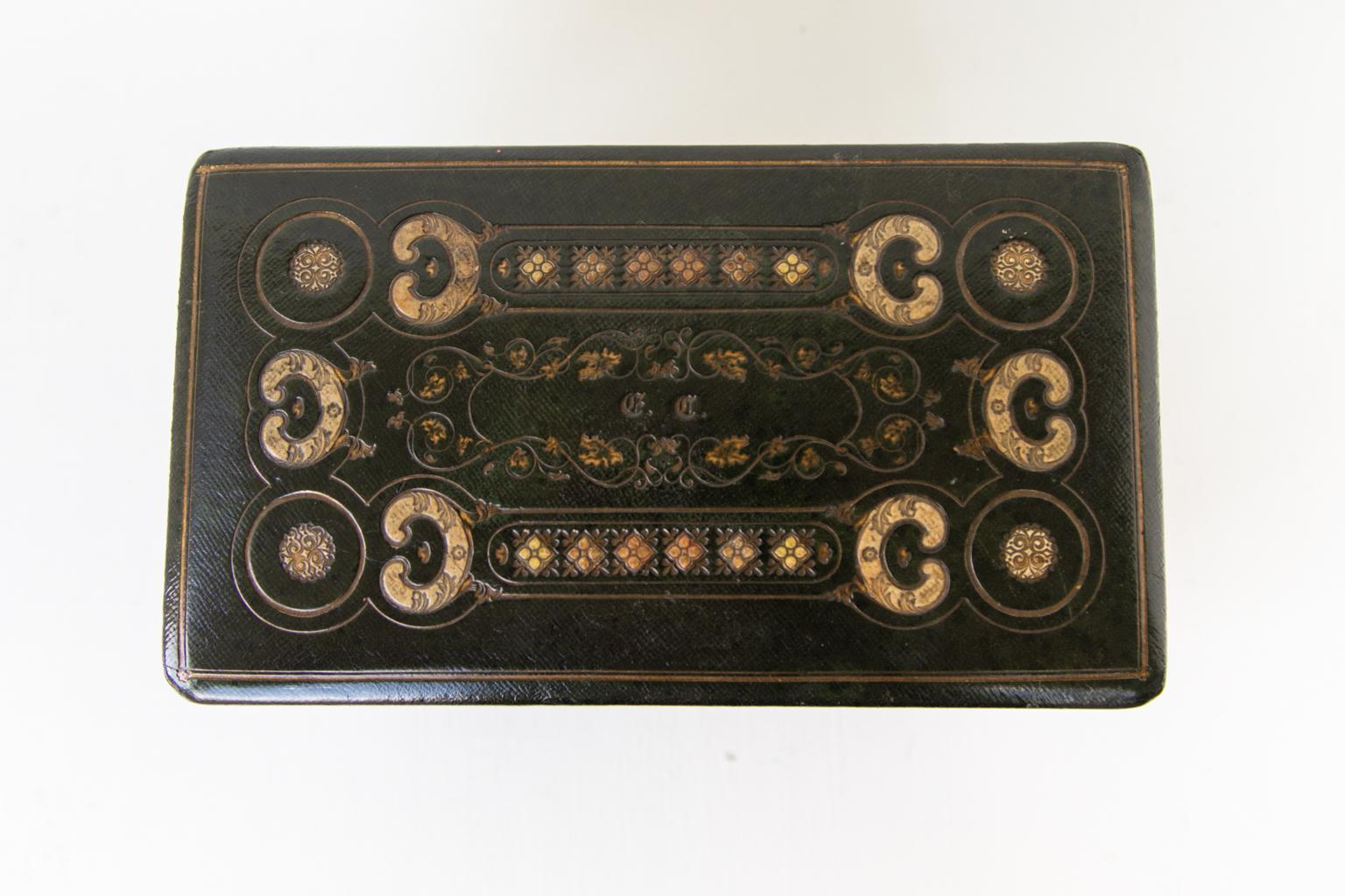 English embossed leather jewelry box, elaborately gold tooled with cartouches and arabesques on the four sides and top, raising the top reveals a removable tray with storage below. The drawer has an etched mother of pearl knob.