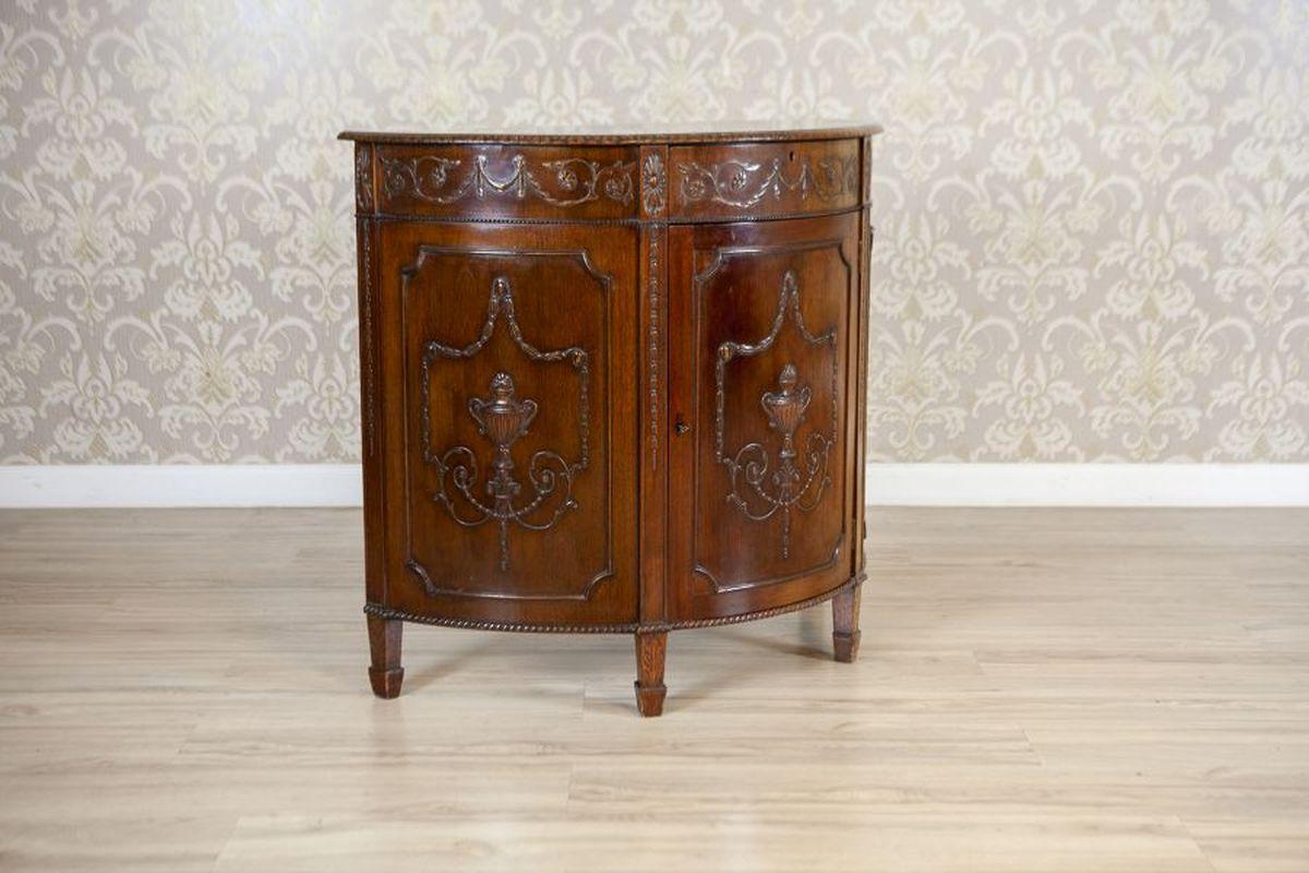 Armadio inglese in stile impero in Oak della fine del XIX secolo

Un mobile in stile impero inglese realizzato in Oak, risalente alla fine del XIX secolo. Il mobile semicircolare è dotato di ante con serratura e di un cassetto, ornato da intagli