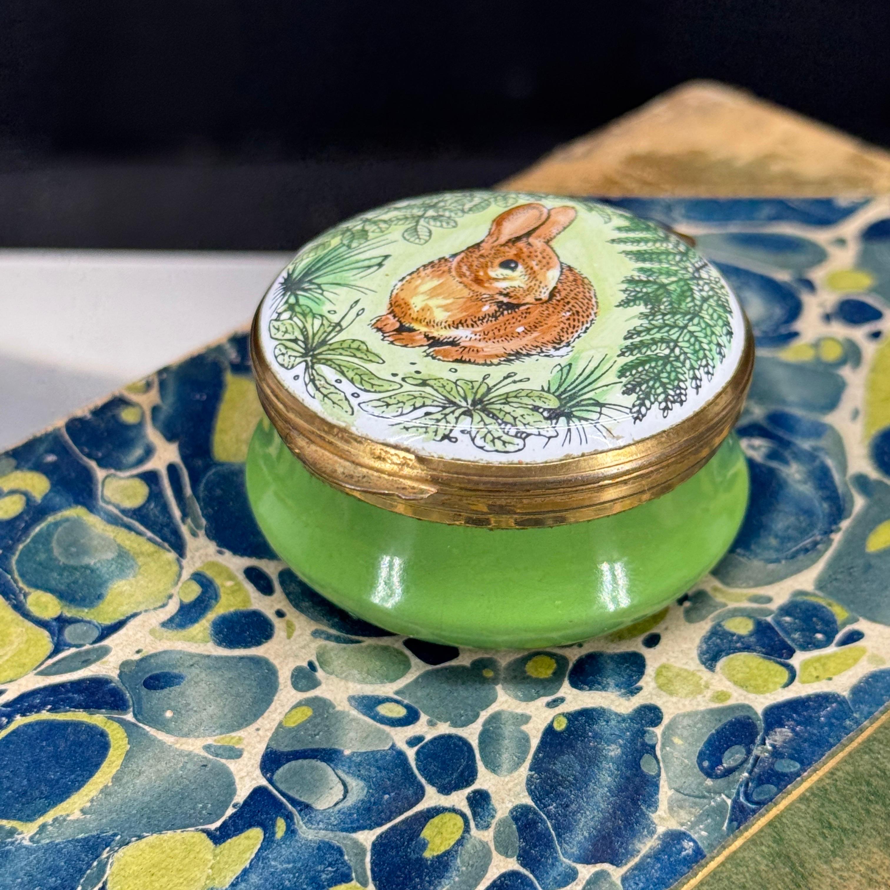 Charming ceramic trinket, pill or small jewelry box with an adorable rabbit on the front, surrounded by lush greenery. This piece would certainly be a fantastic addition to an existing collection of these desirable small boxes. Made in England.


